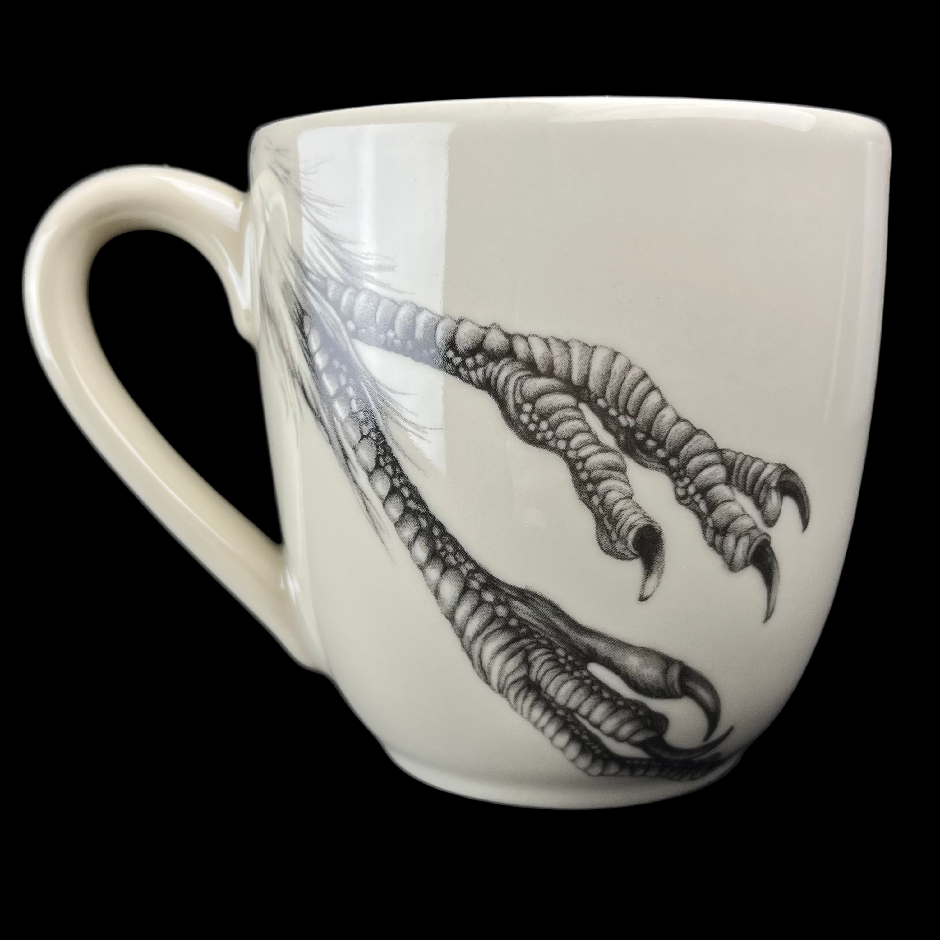 White mug with black claw design on a dark background