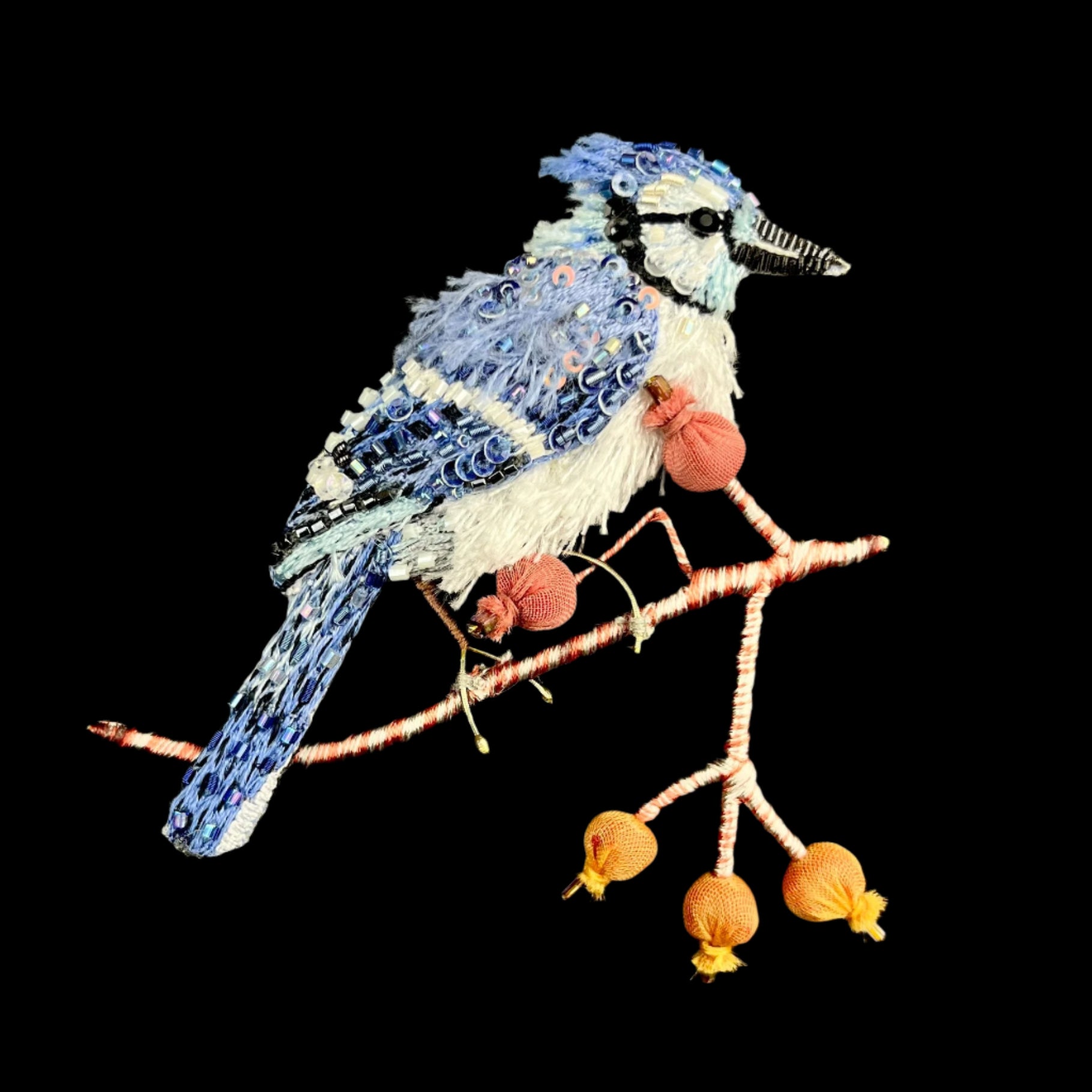 Embroidered blue and white blue jay bird perched on branch with round red berries