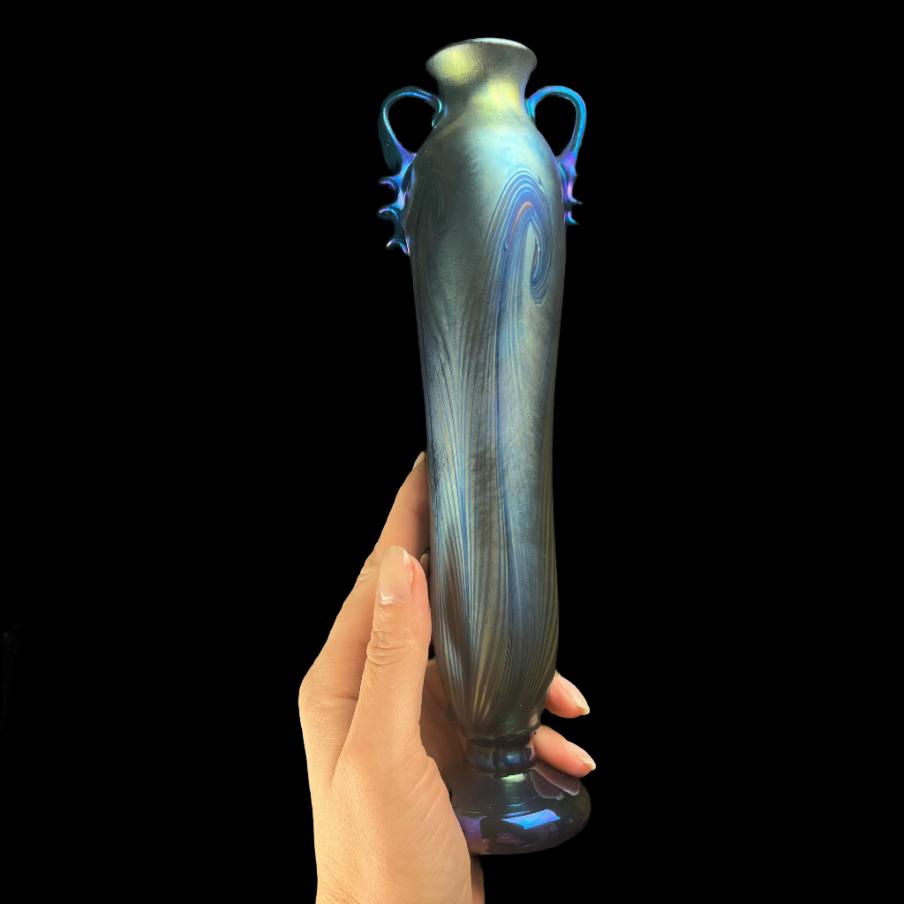 Hand holding a decorative vase against a dark background