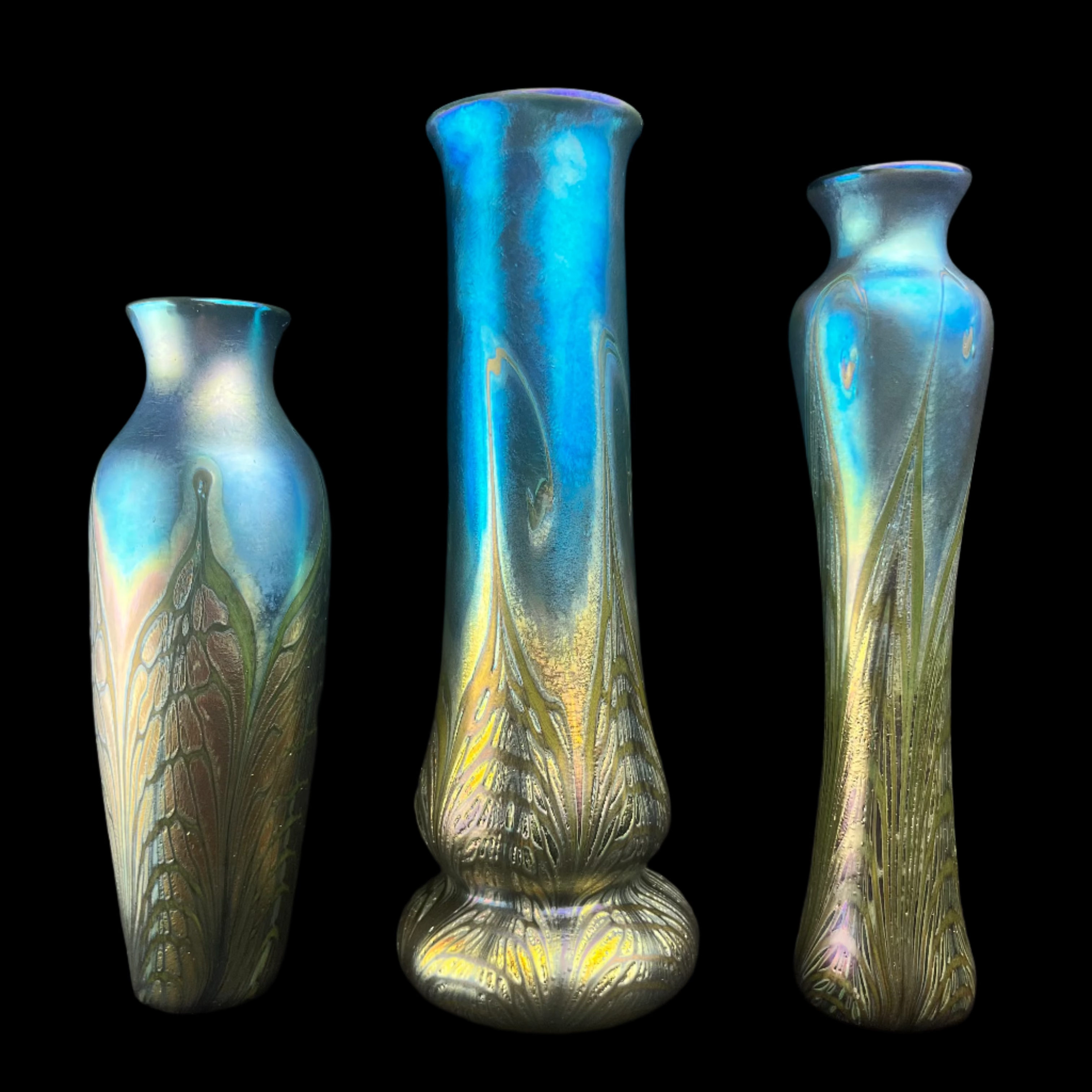 Three iridescent glass vases with leaf patterns on a black background