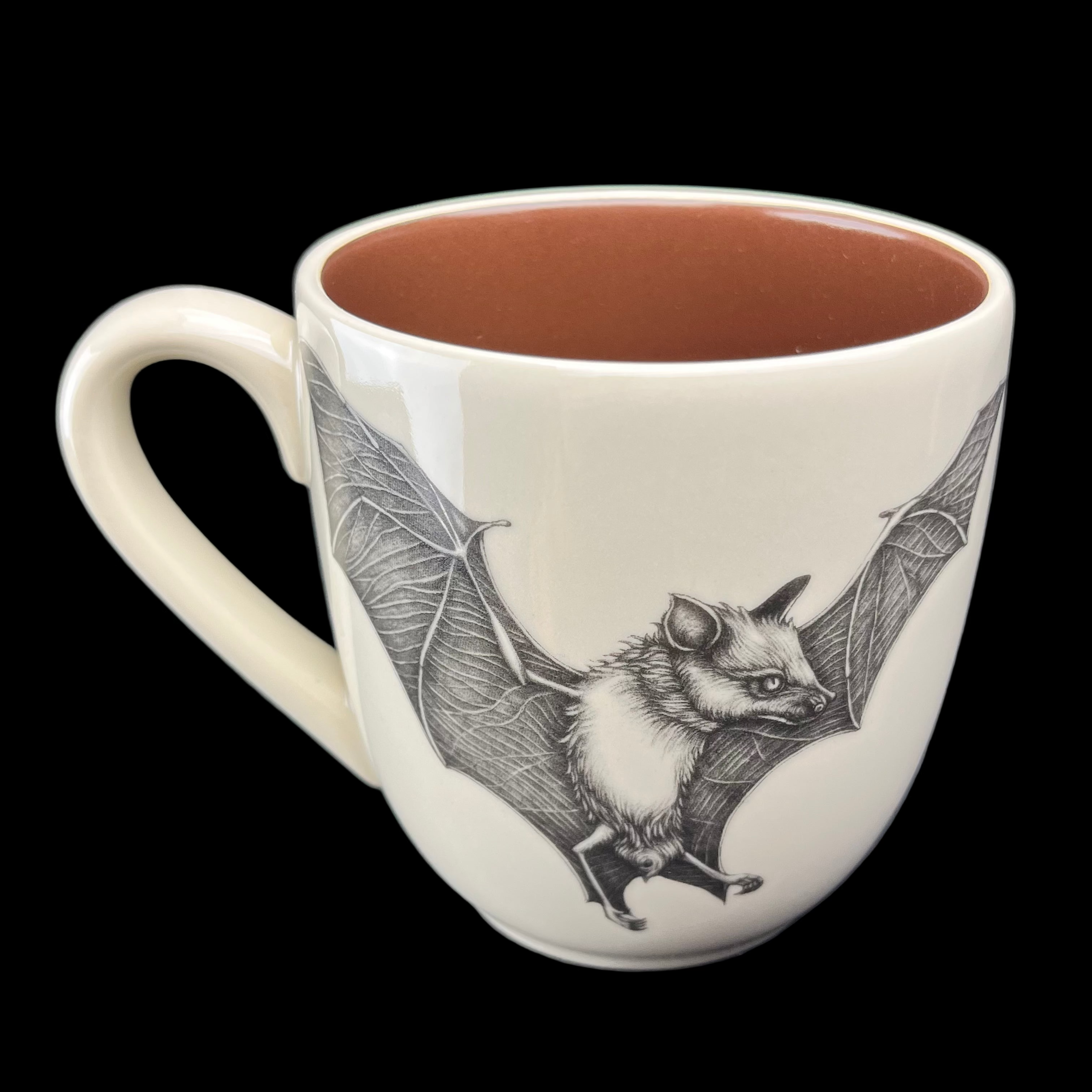 Ceramic mug with a bat illustration on a dark surface