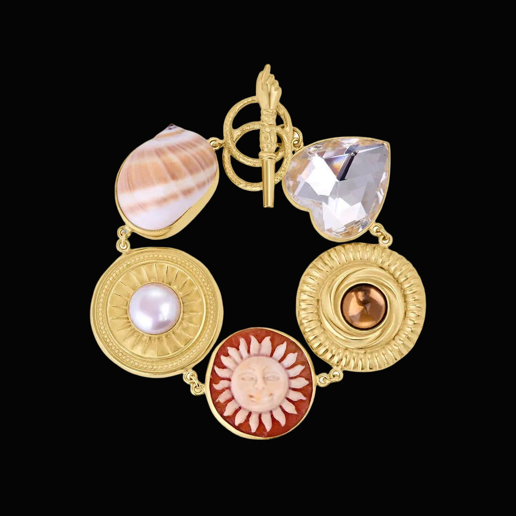 Large charm bracelet with organic materials like shells and vintage glass on gold
