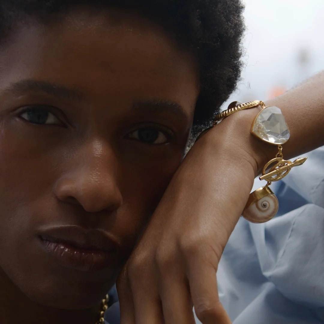 female model wearing a bracelet of large charms strung together on delicate chain.