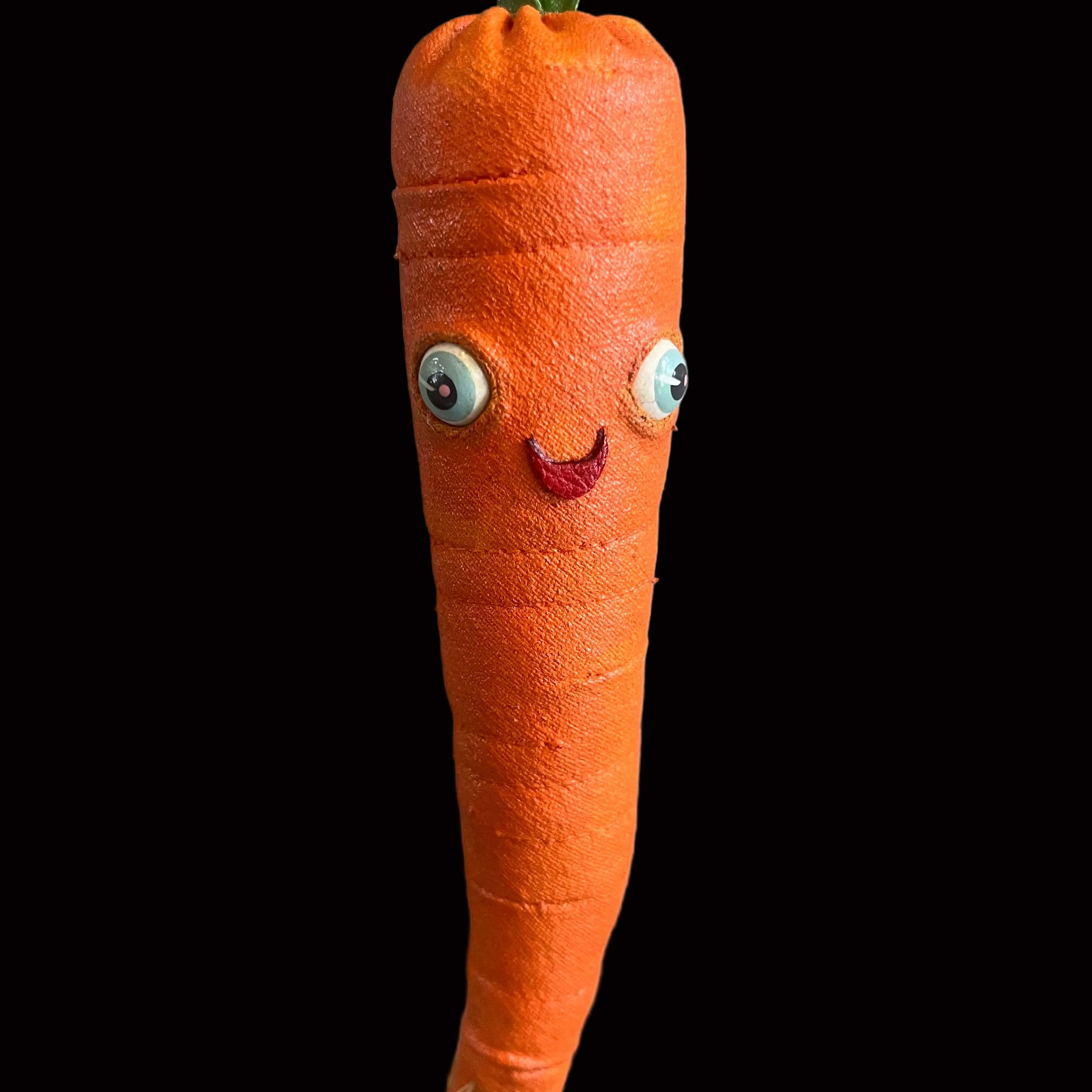 Whimsical carrot-shaped decorative figure with blue eyes and smiling red lips set against black background.