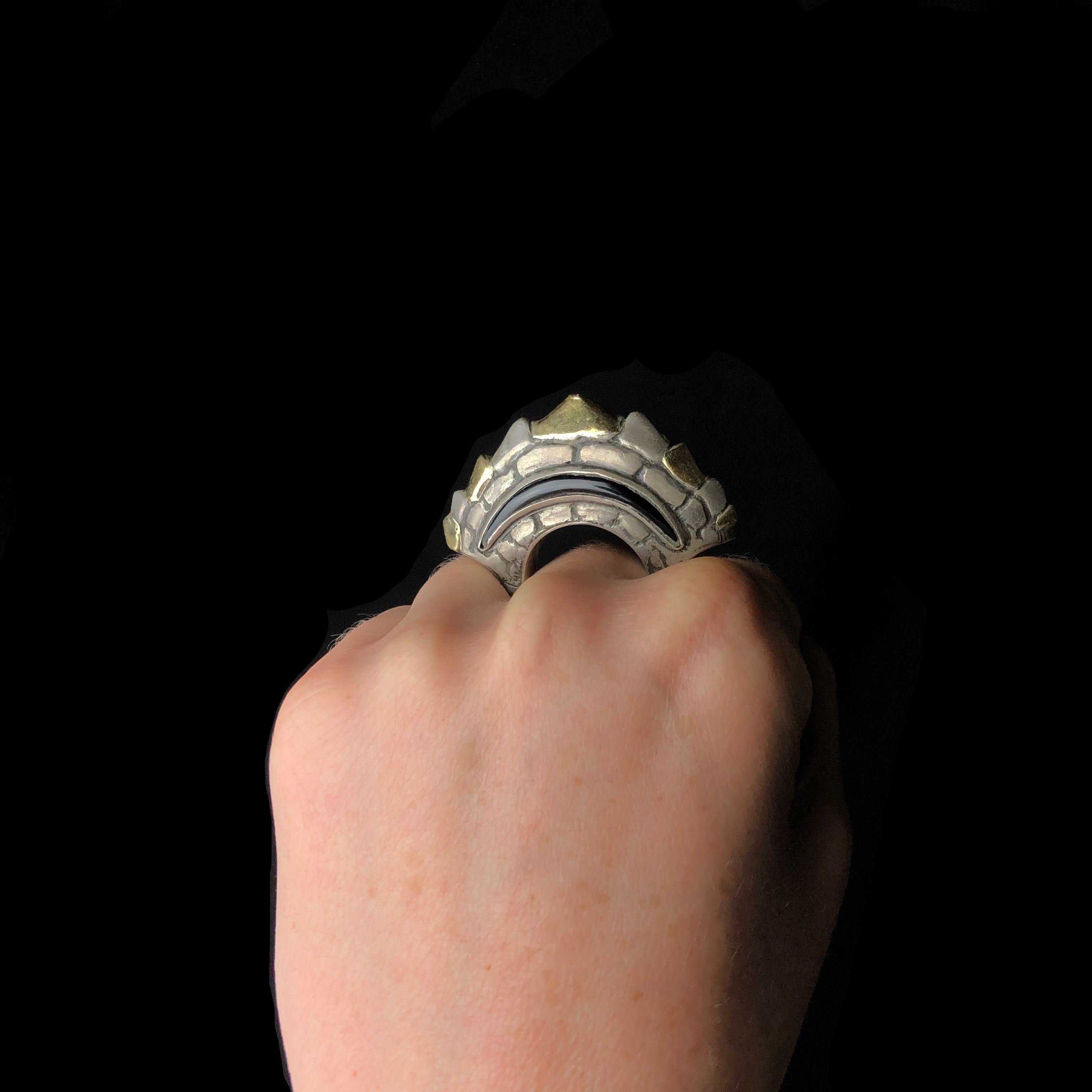 Hand with a dramatic metallic ring against a black background