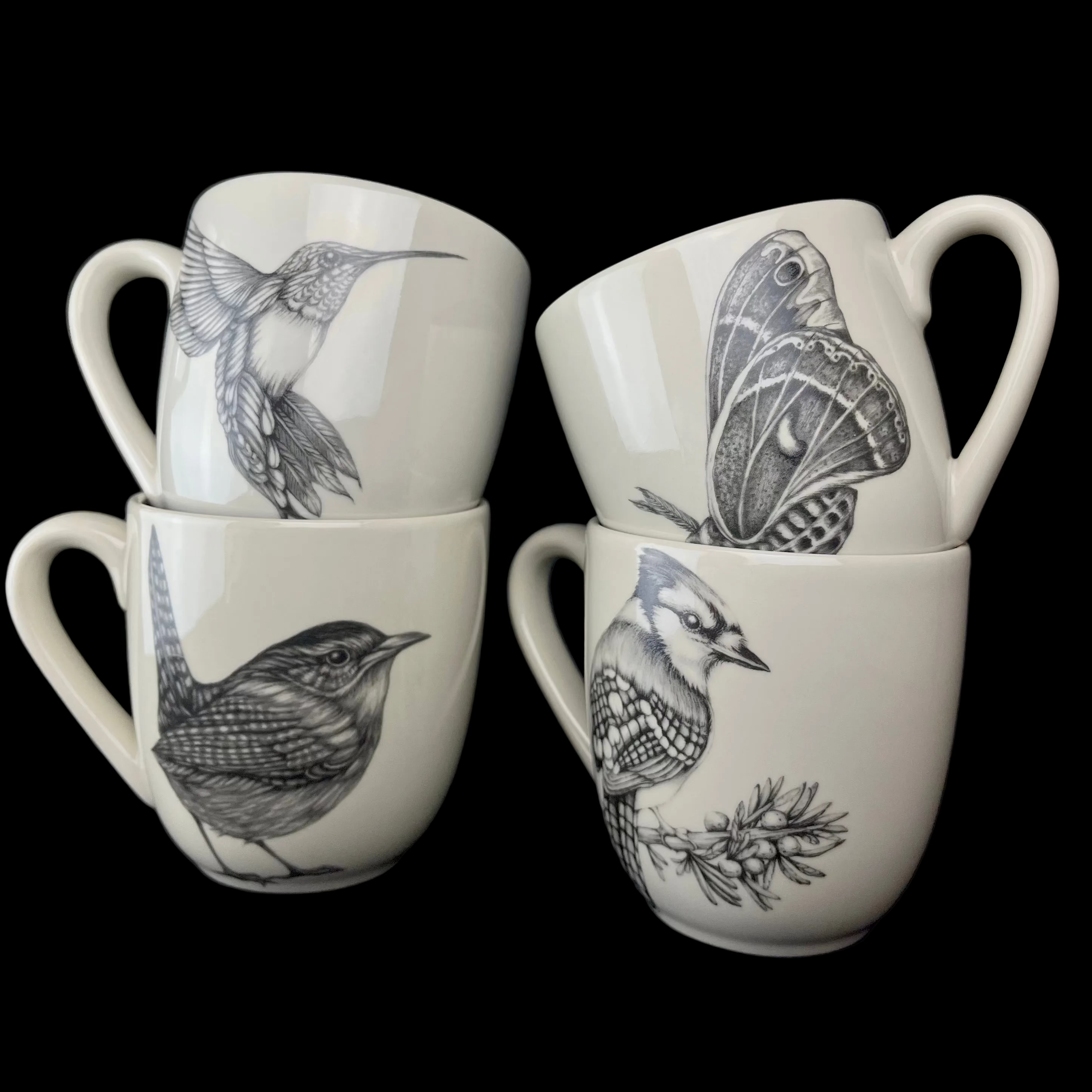 Four white mugs with black animal illustrations on a dark background