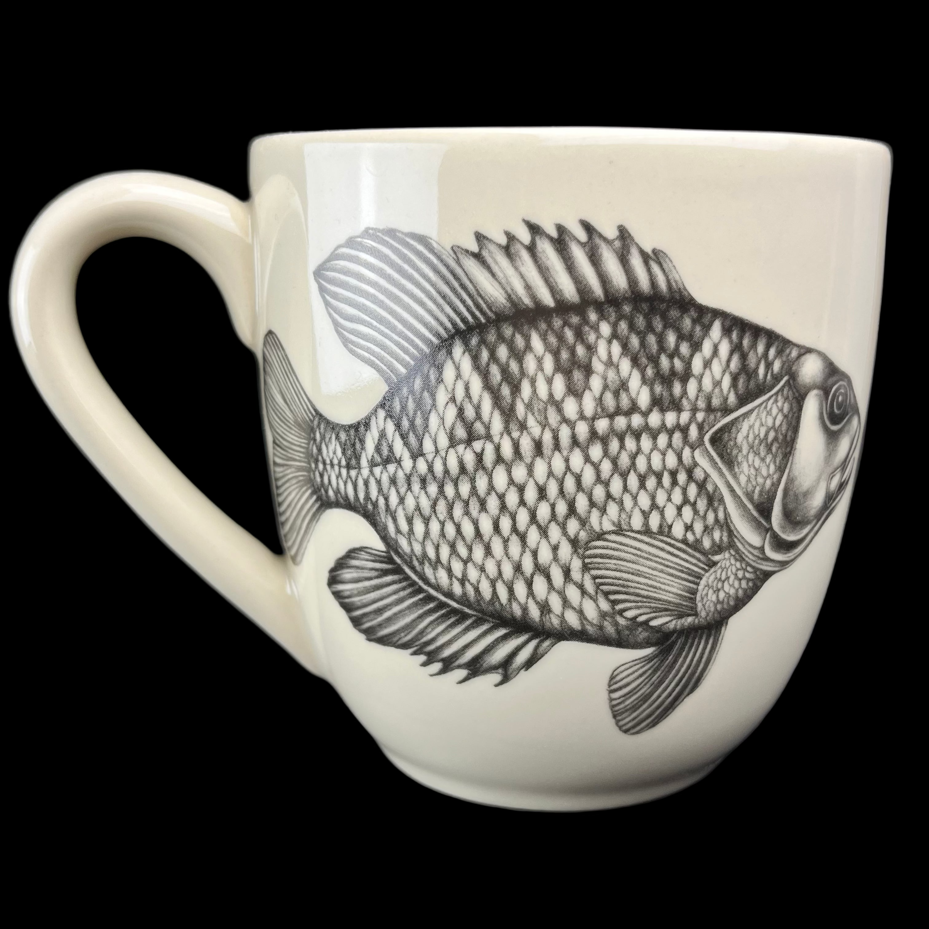 White mug with black fish illustration on a dark background