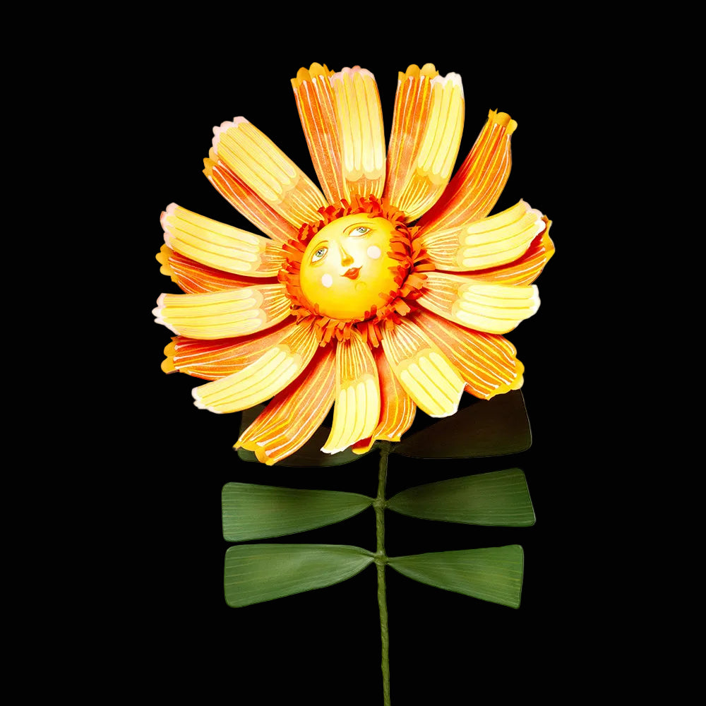 Bright yellow and orange flower sculpture with green stem and a smiling face in the center. 