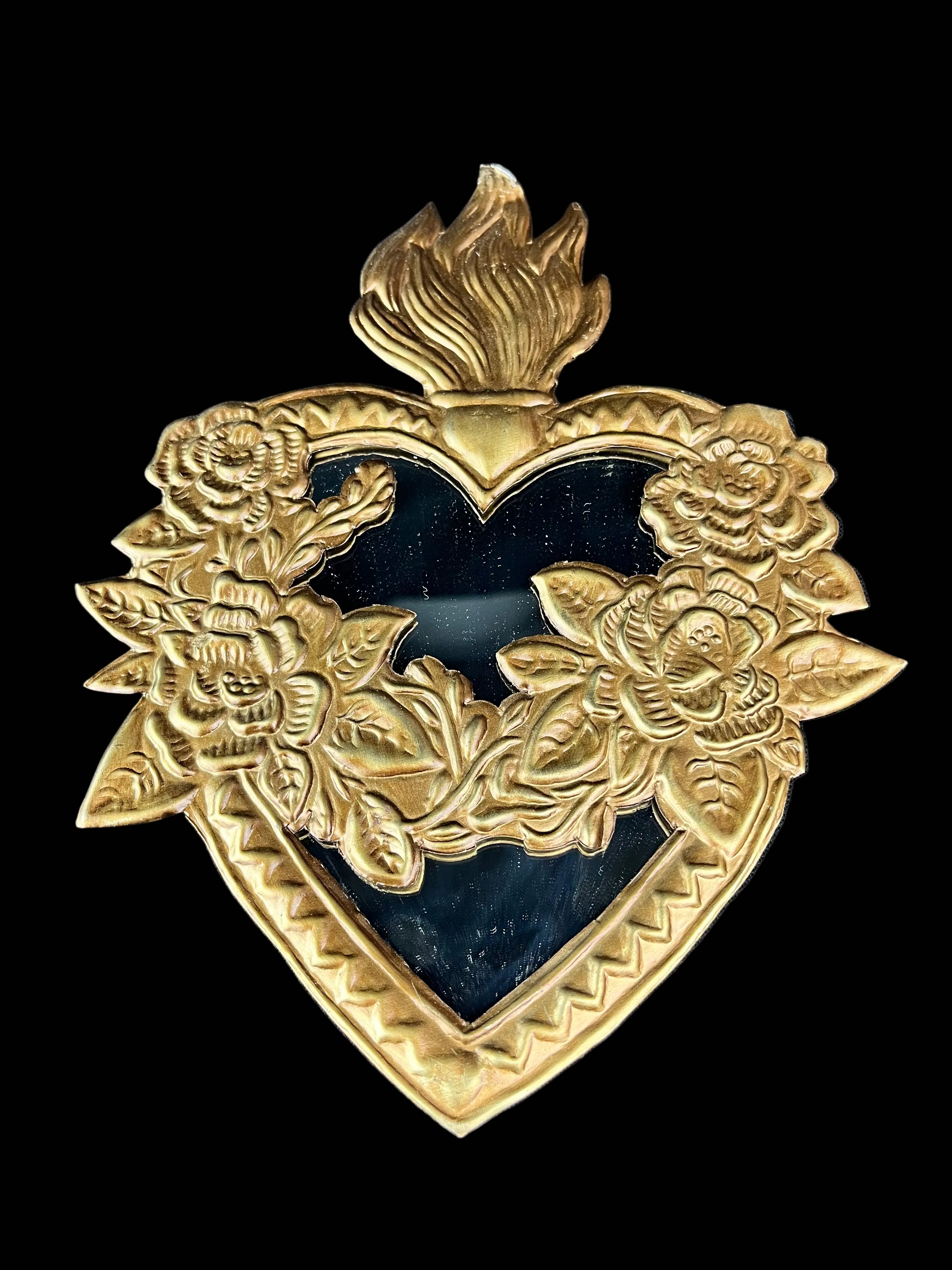 Decorative gold heart-shaped emblem with floral designs on a blue fabric background