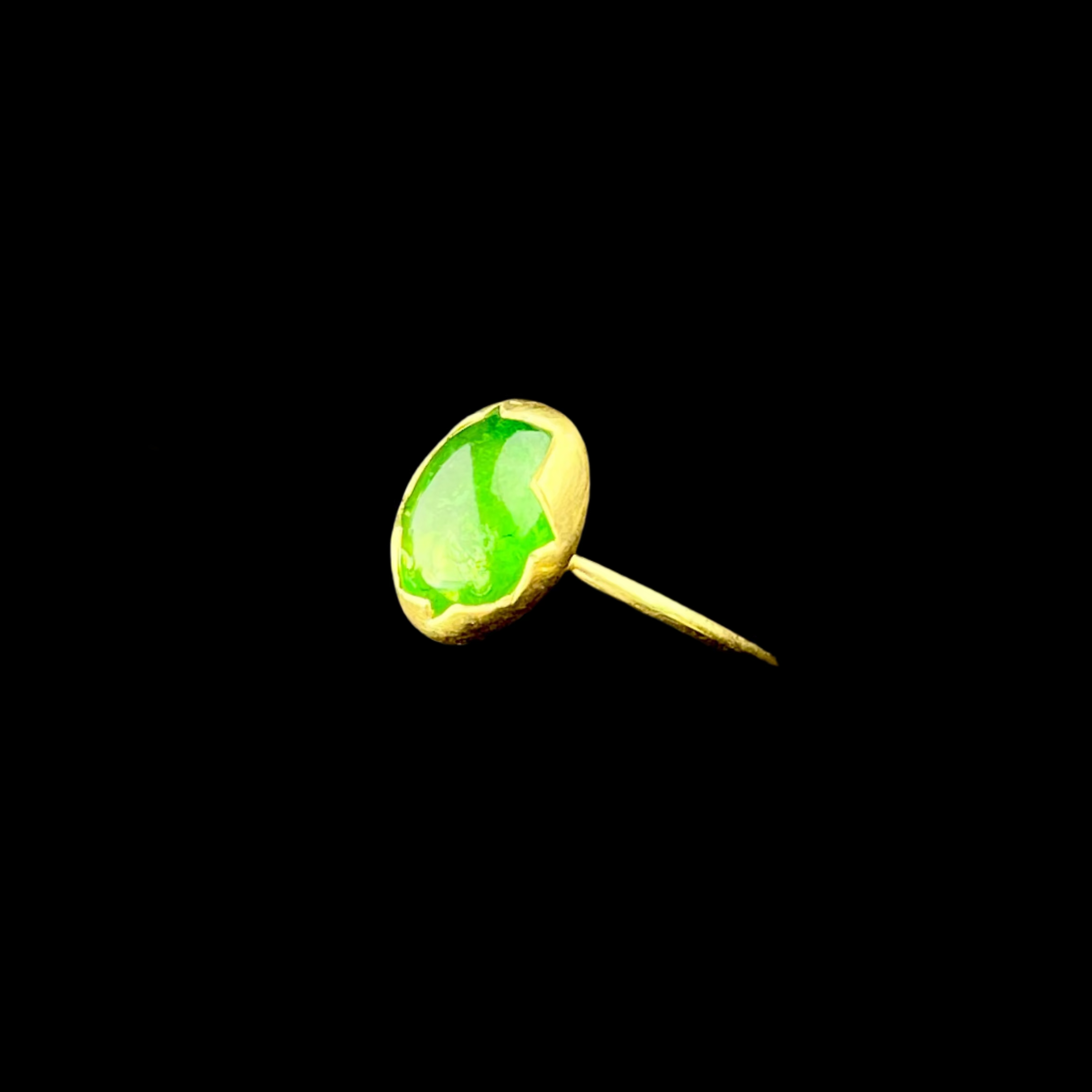 Gold ring with a green gemstone on a dark background
