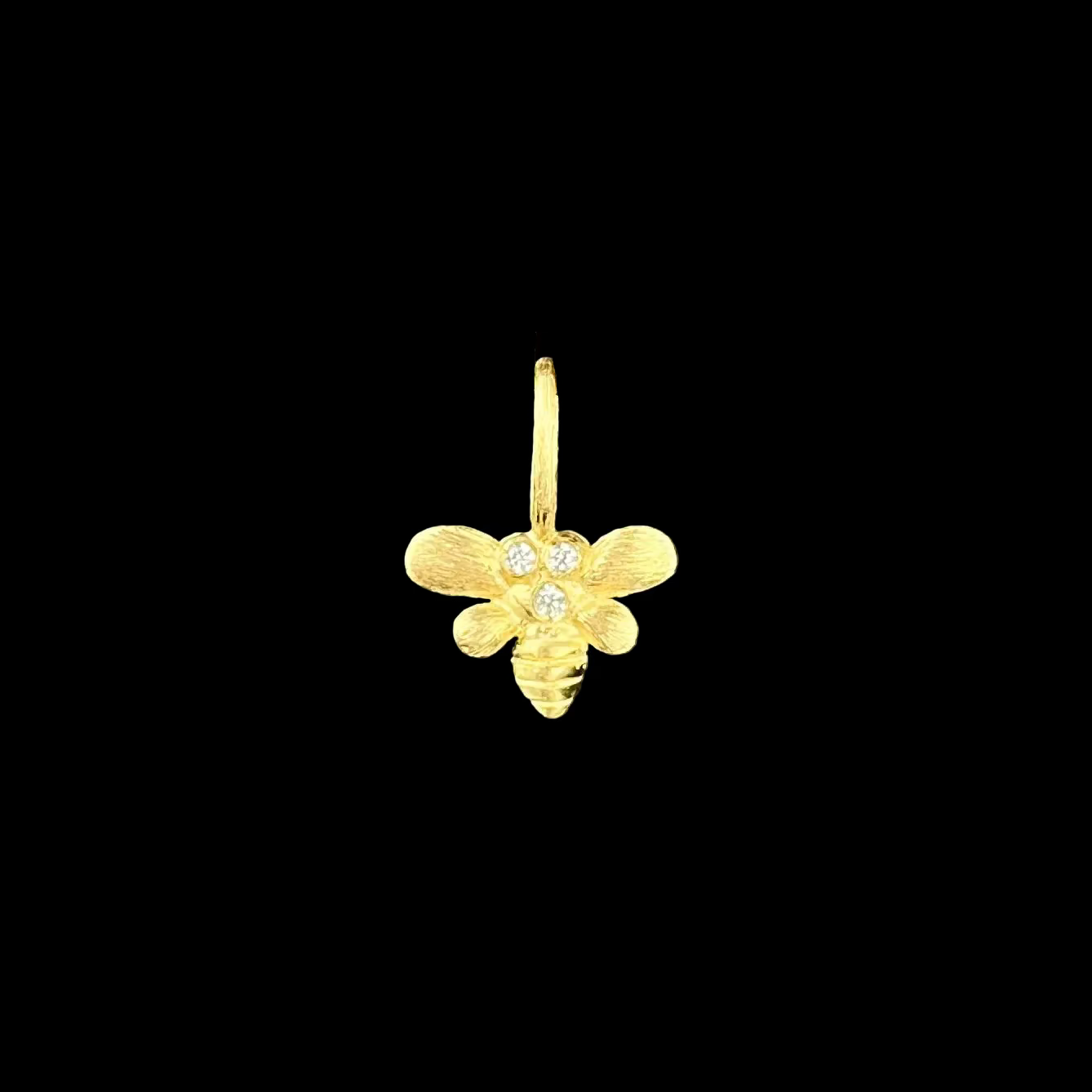 Gold bee-shaped earring on a black background