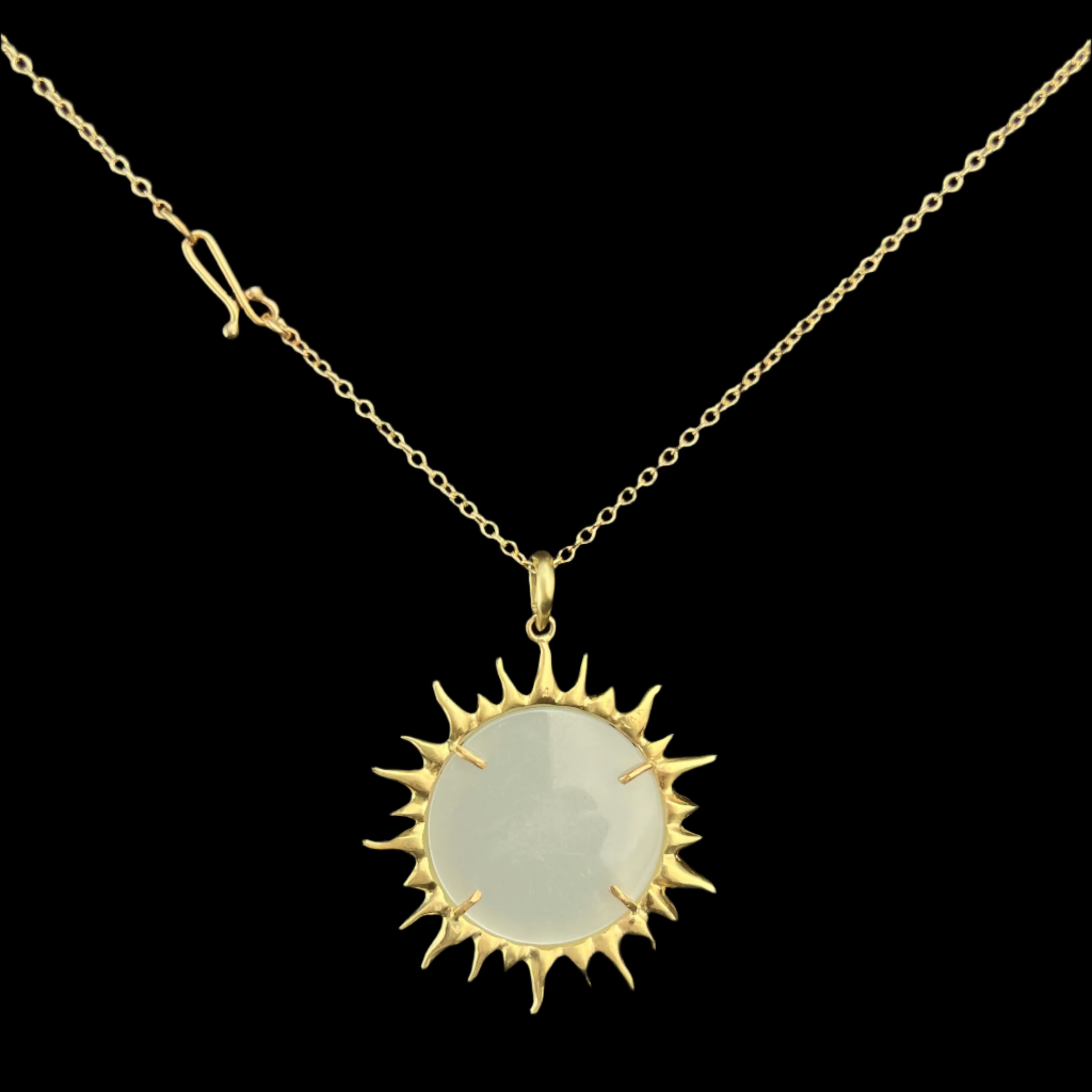 Gold sun-shaped pendant necklace on a black background