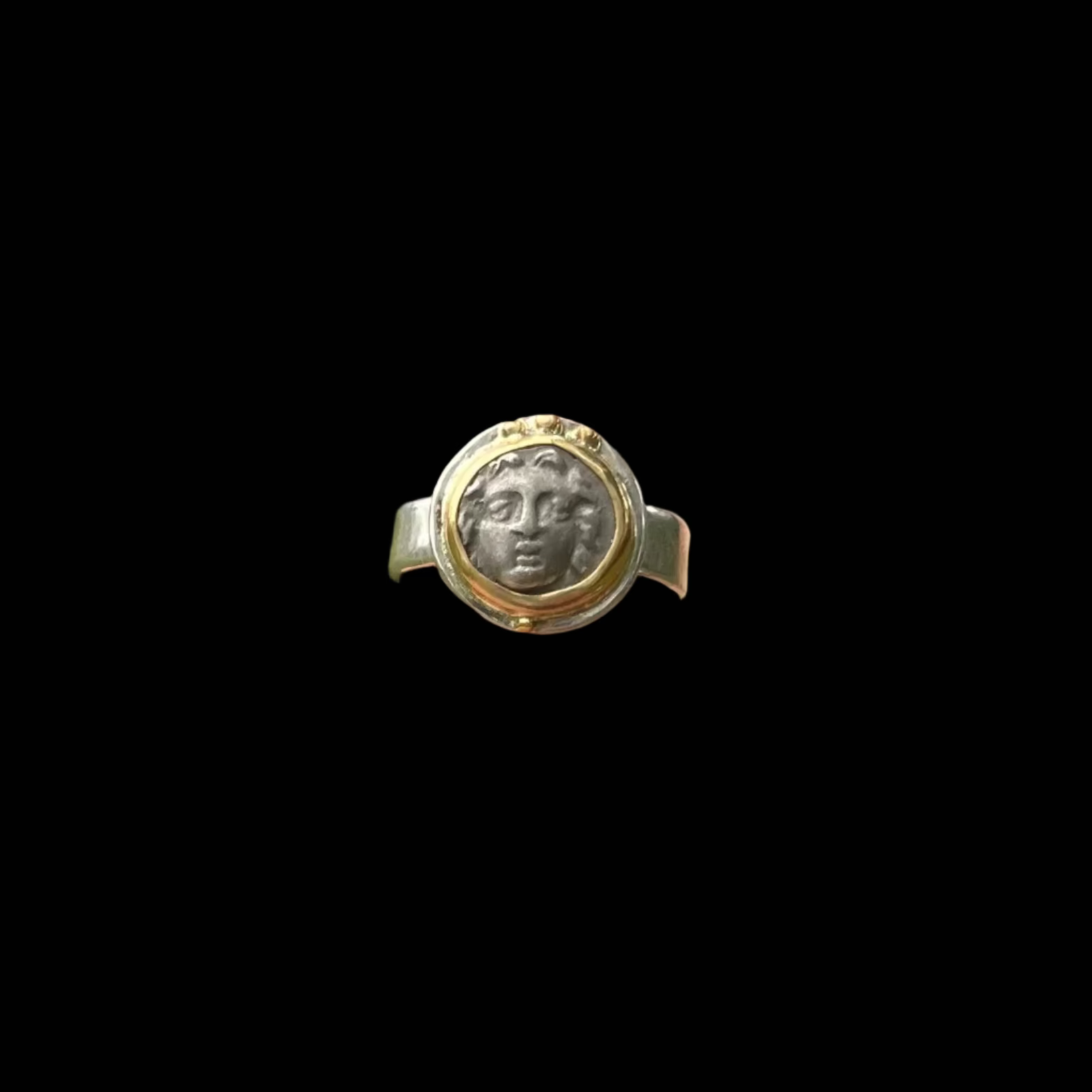 Hand wearing a decorative ring with a green outdoor background