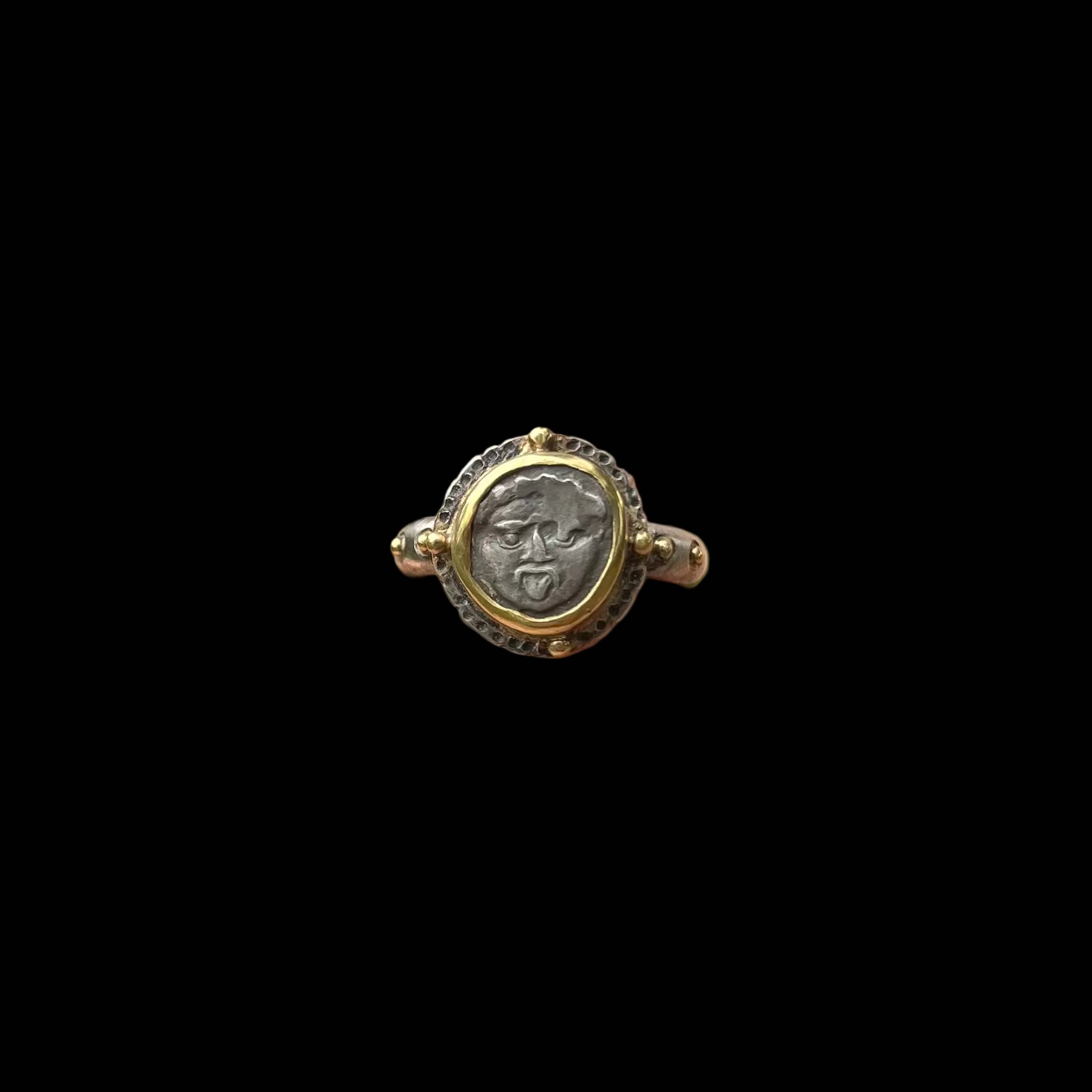 Gold and silver ring with a circular design against a black background
