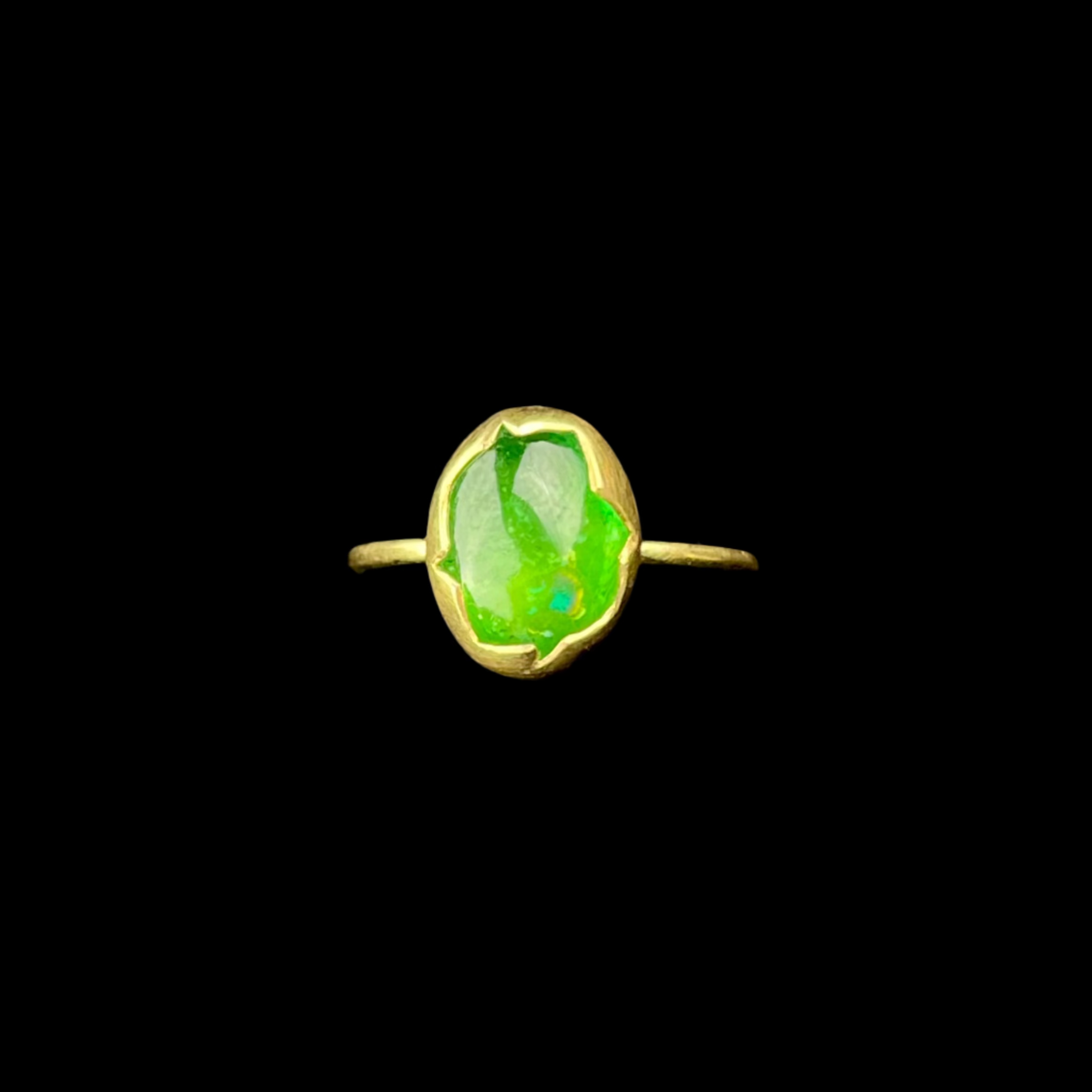 Gold ring with a green stone on a black background