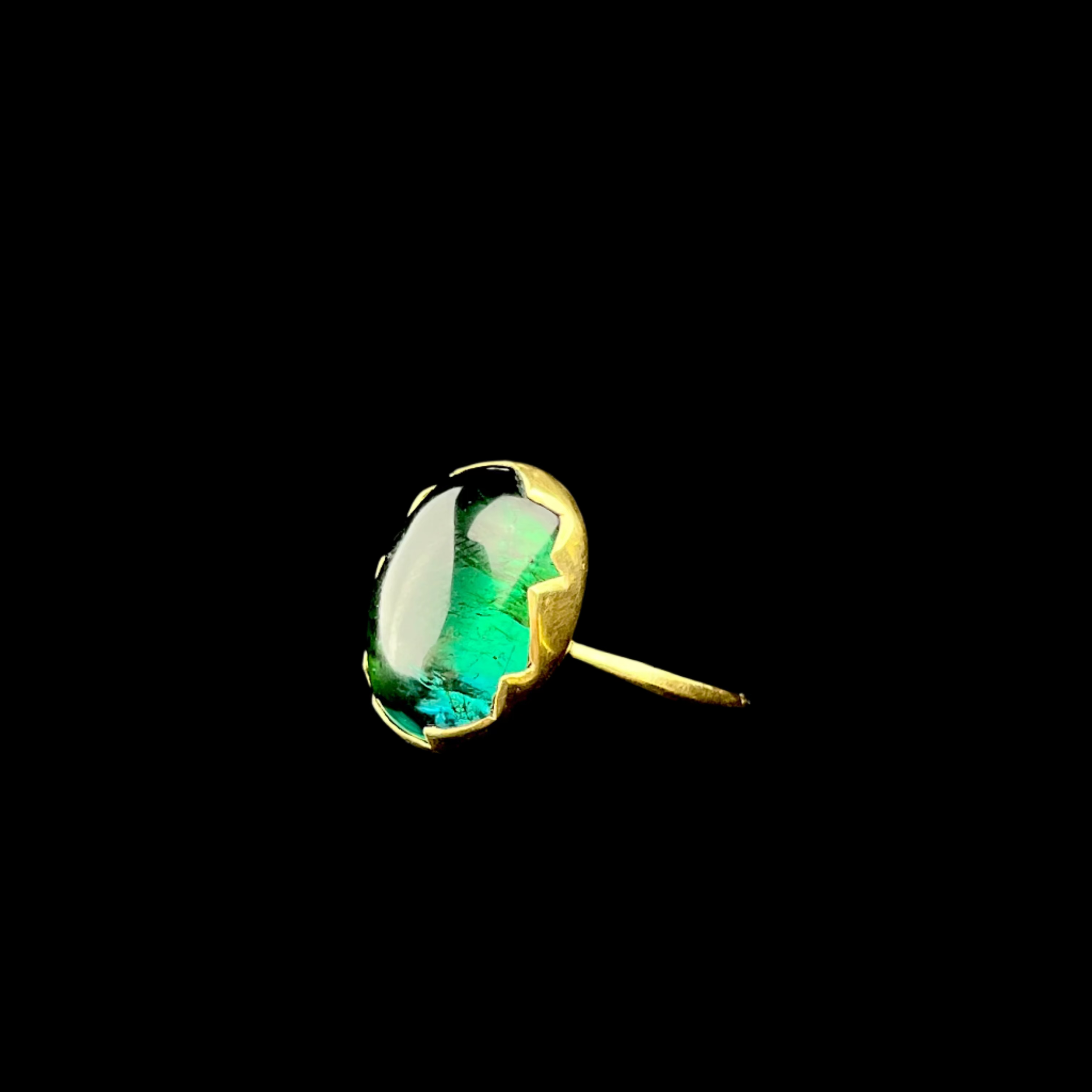Gold ring with a green gemstone on a black background