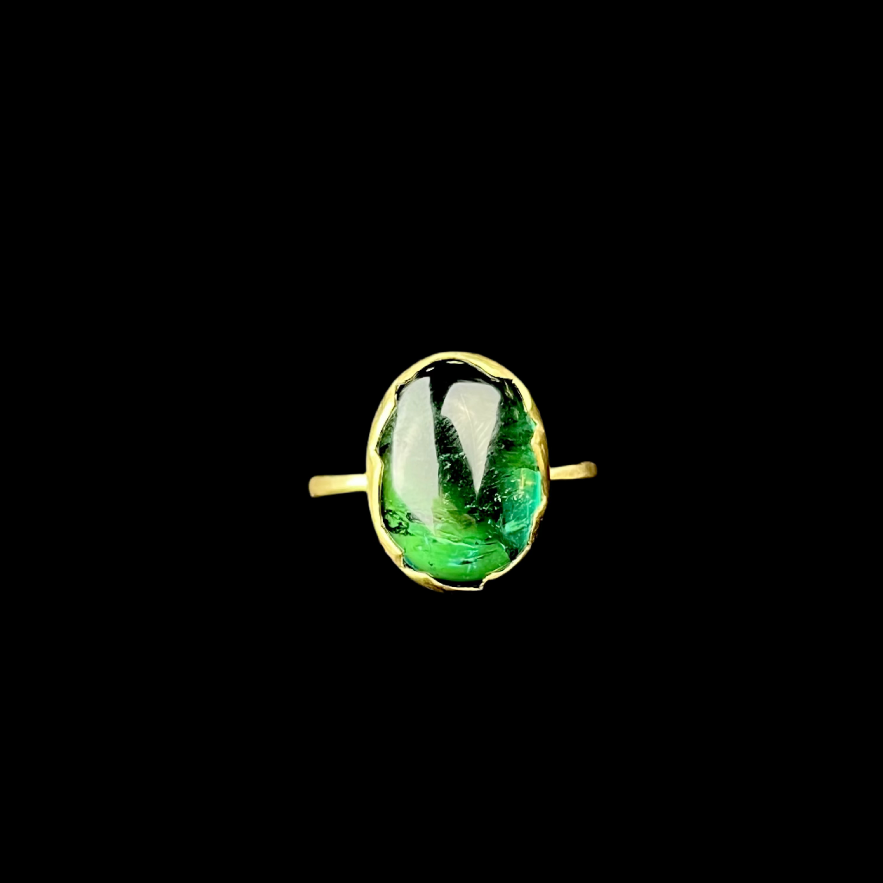 Gold ring with a green gemstone on a black background