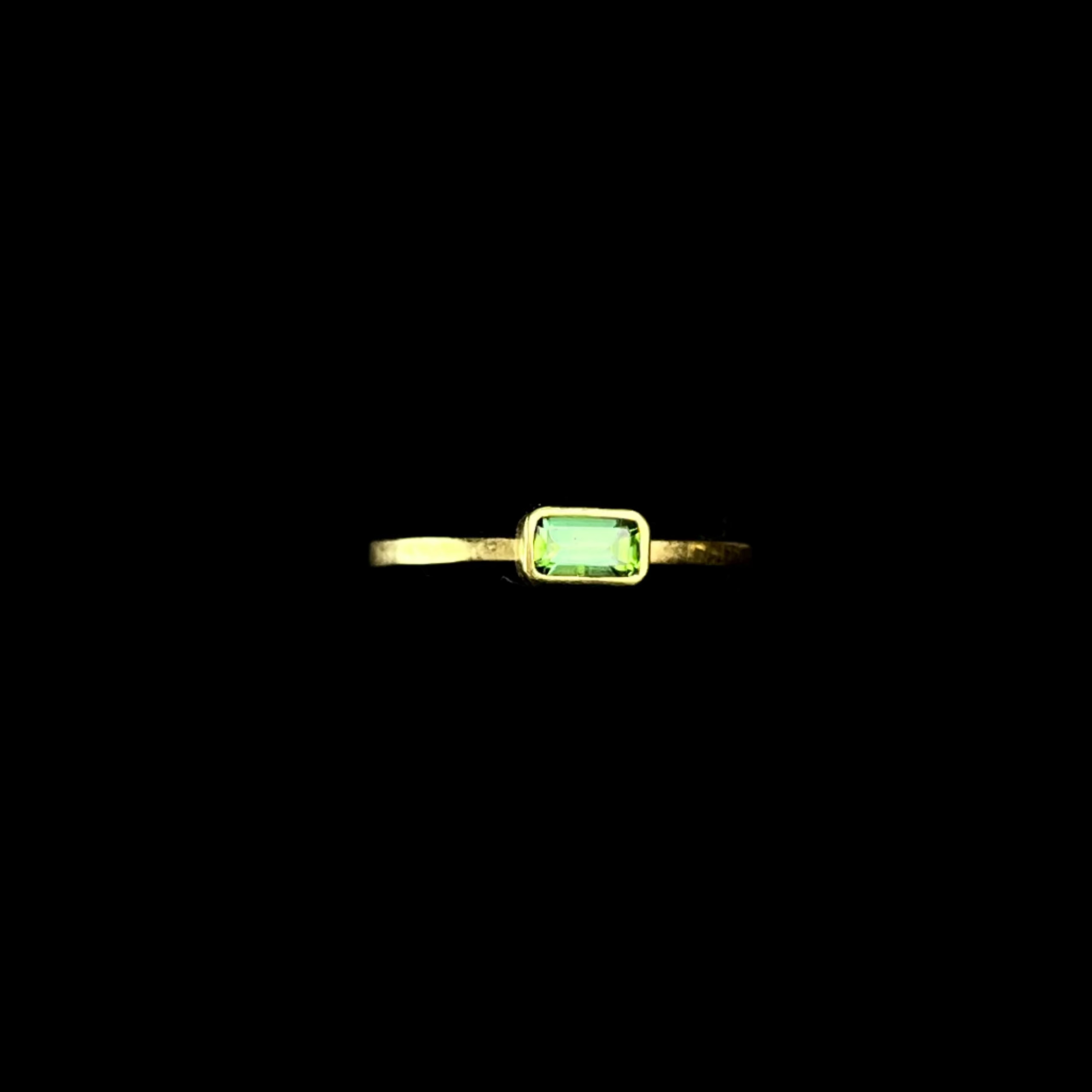 Gold ring with a green gemstone on a dark background