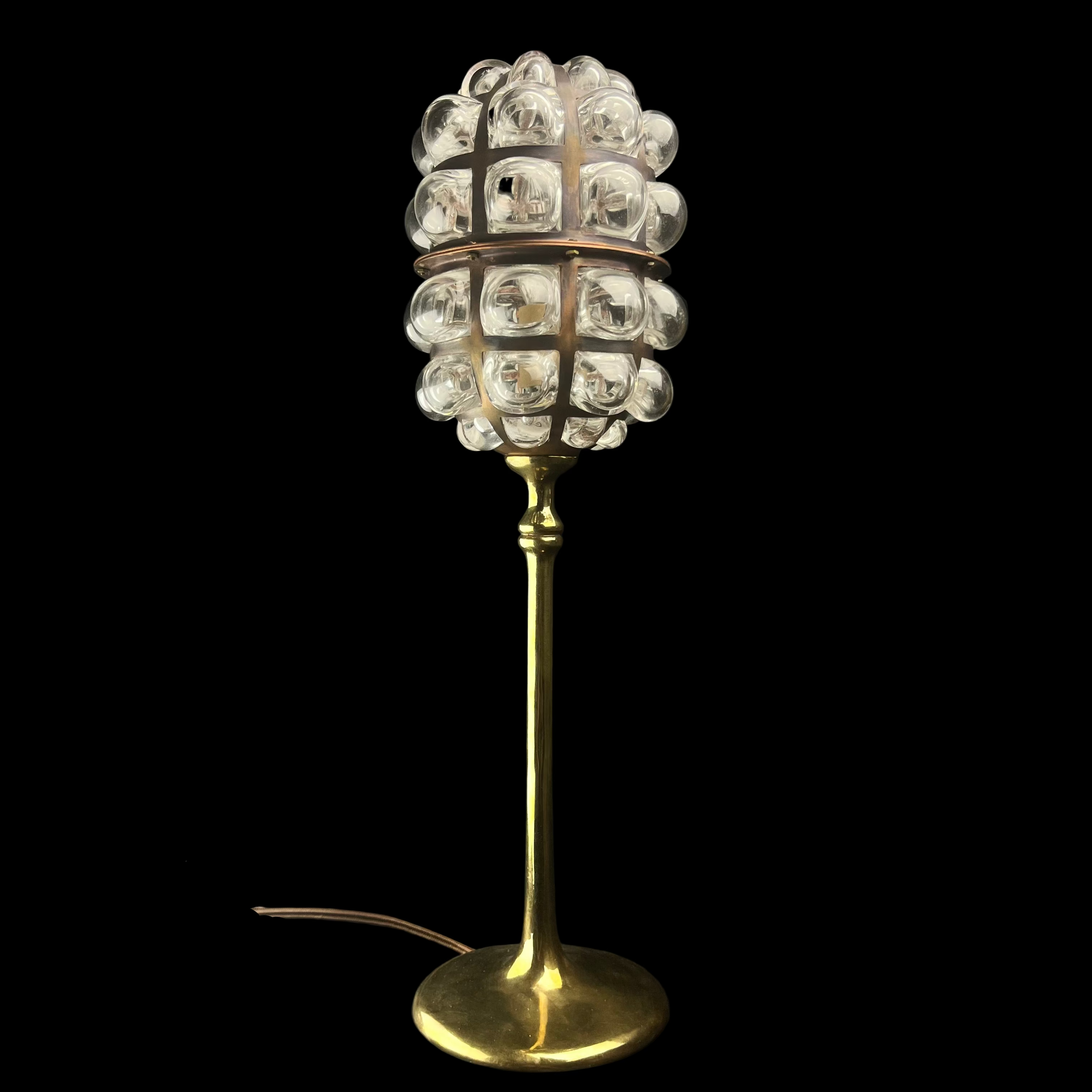 Decorative table lamp with a gold base and glass ball shade on a dark background