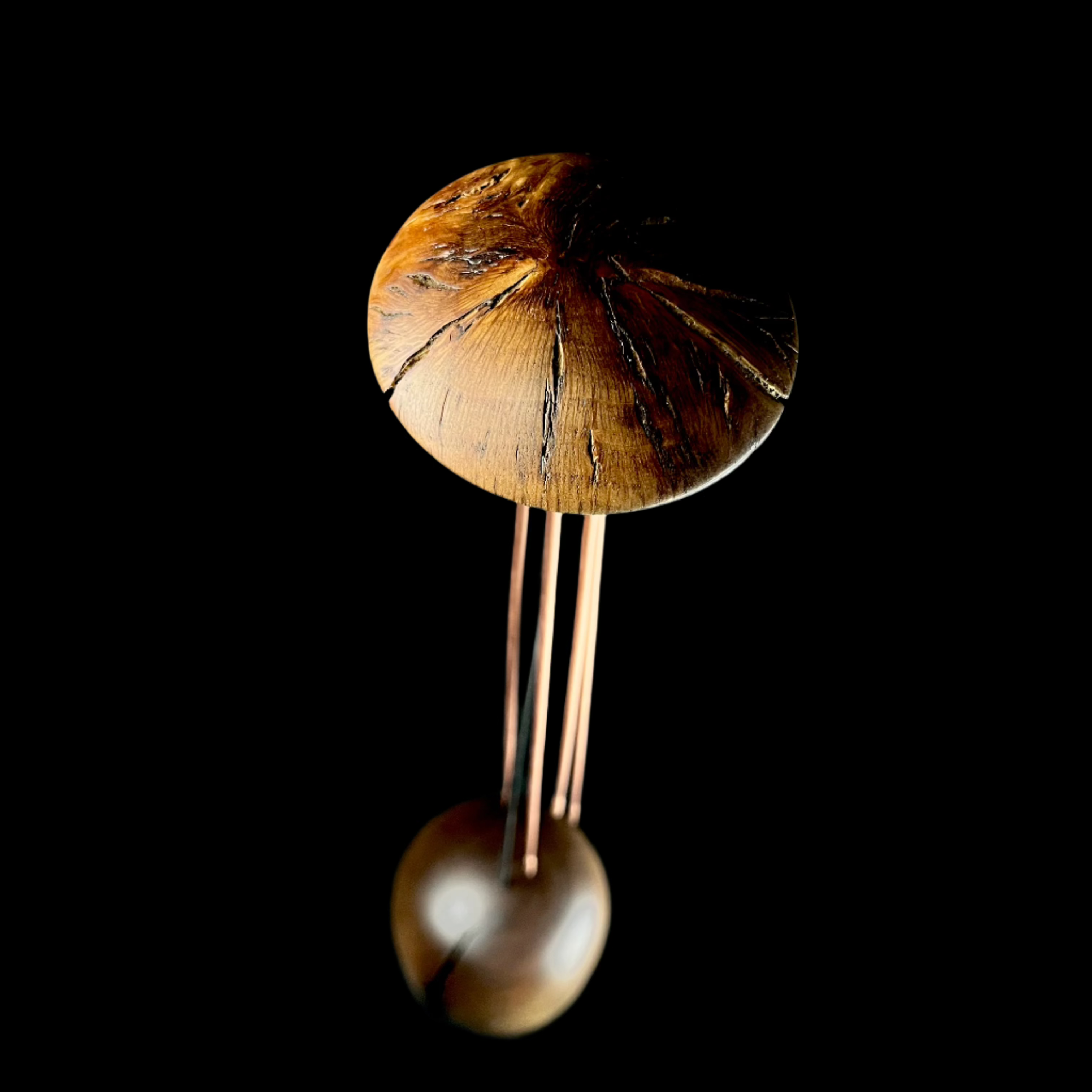 Wooden sculpture with three vertical elements on a dark surface