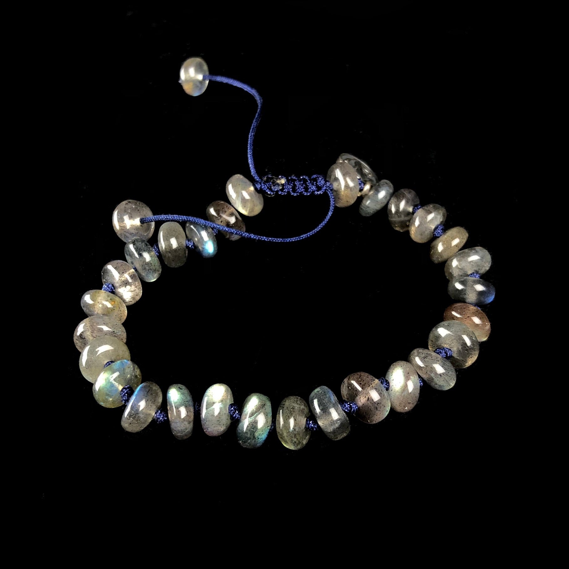 Translucent iridescent grey, blue and green colored stones on dark blue knotted cord