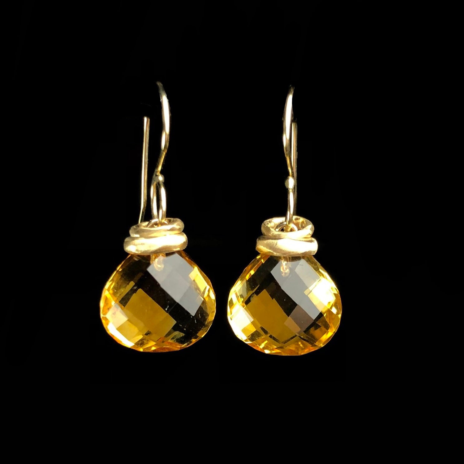 Golden yellow stones with facets hanging from gold earring wires 