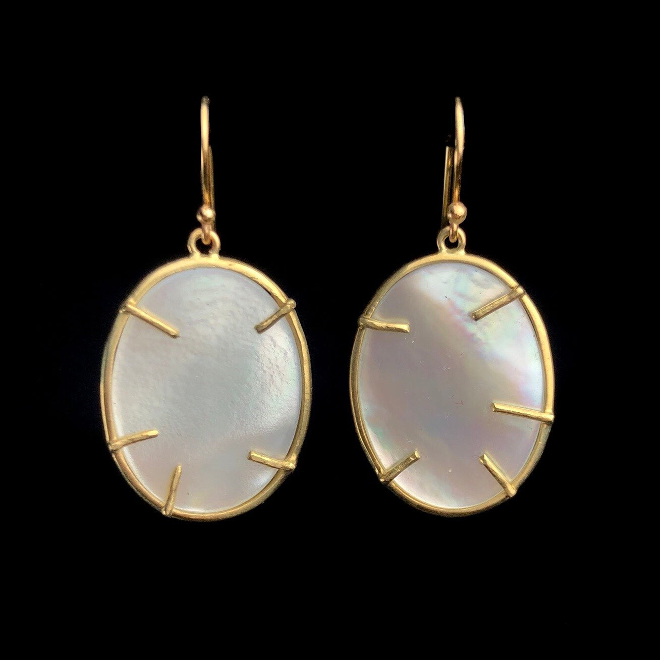 Iridescent white oval discs with gold prong settings on gold earring hooks