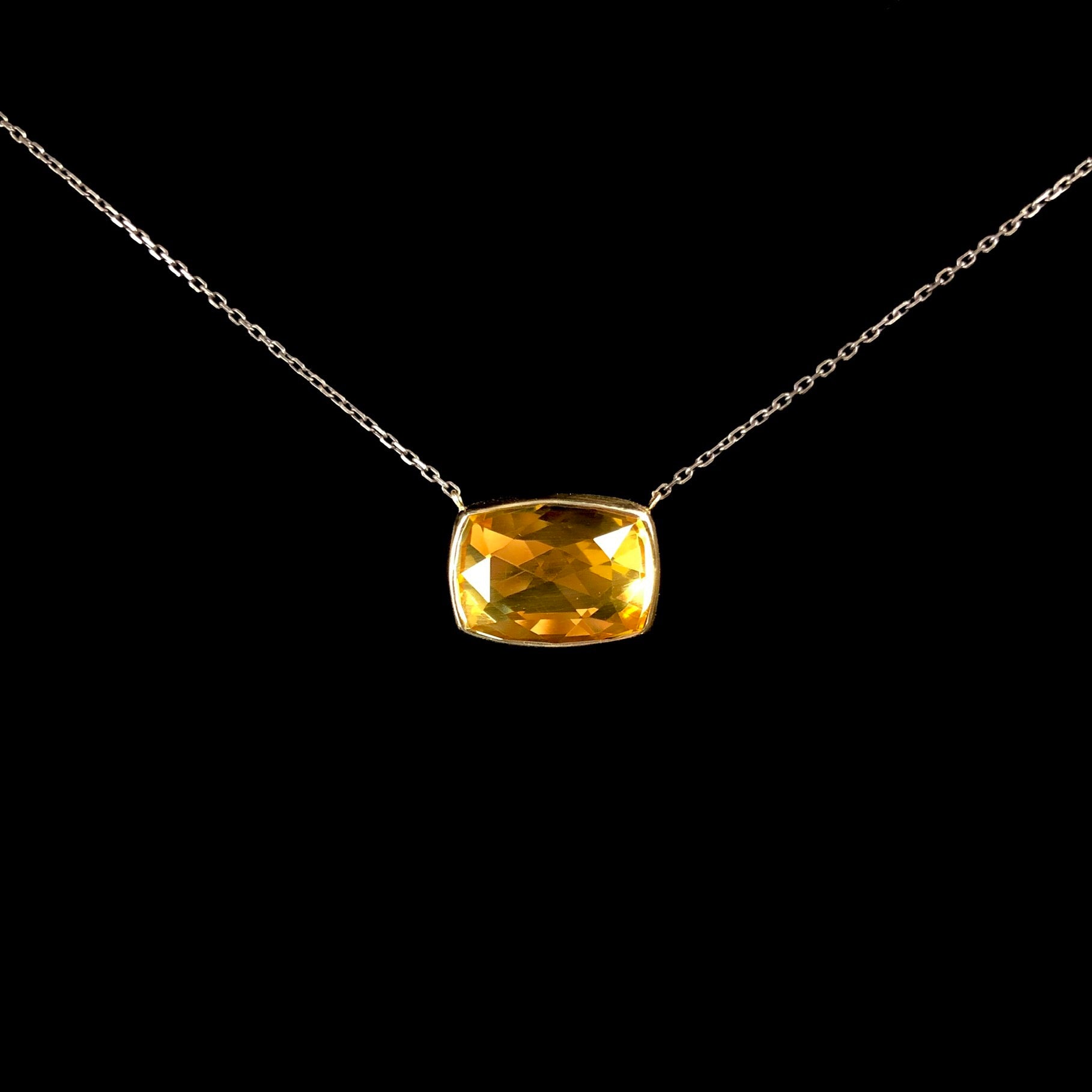 Yellow rectangular stone set in gold hanging on oxidized silver chain