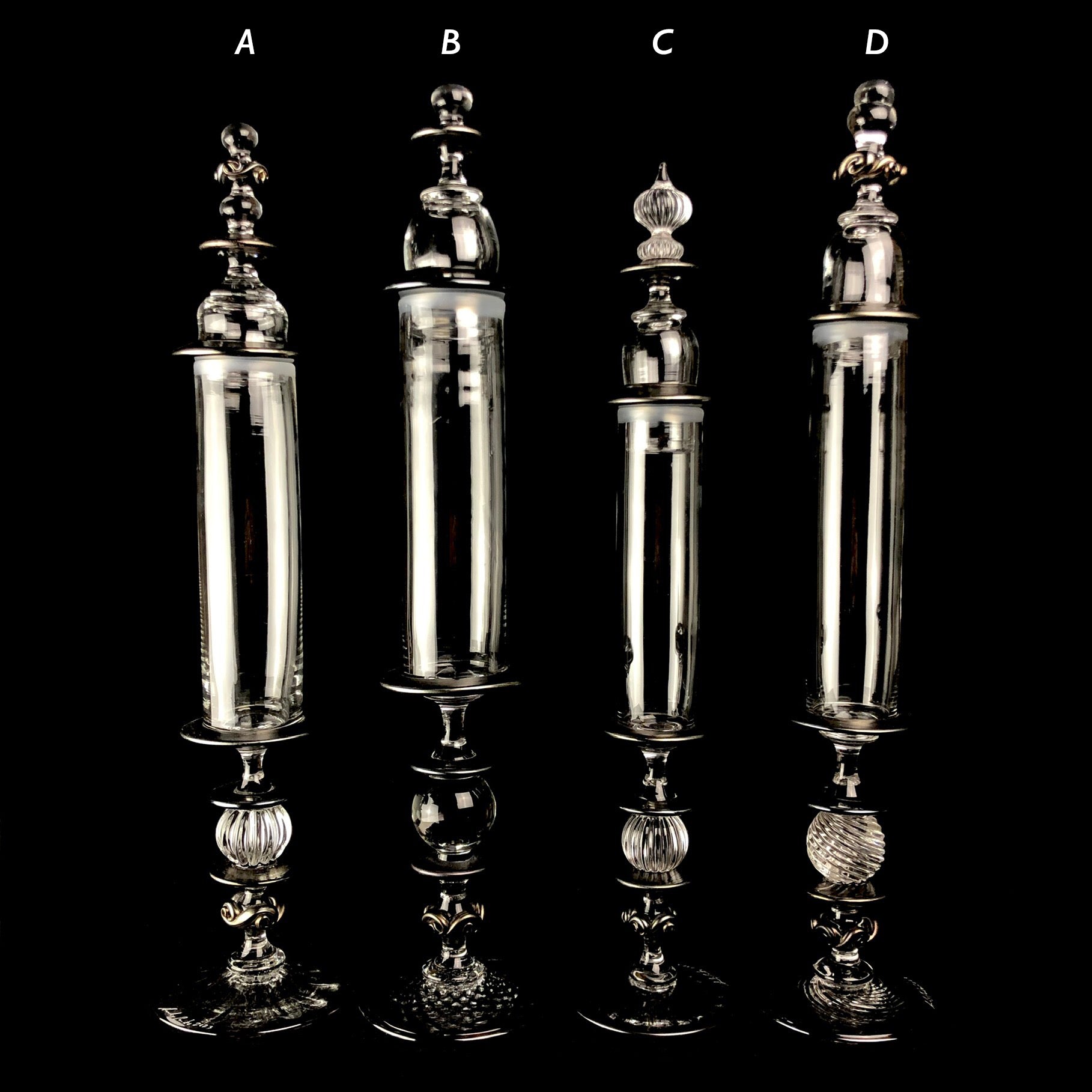 Four clear glass cylindrical containers with fancy lids and stands