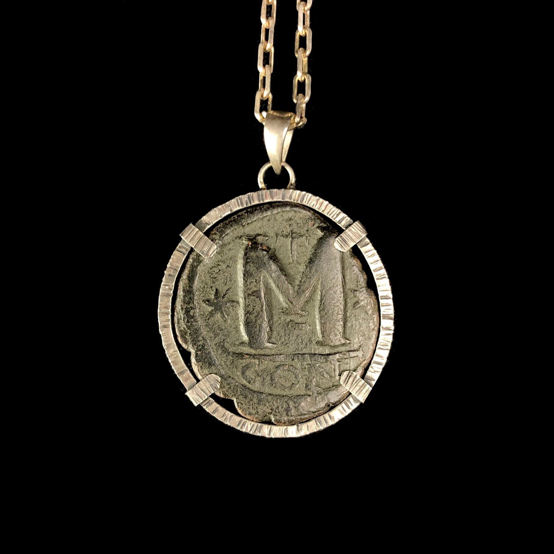 Bronze coin with the letter M in silver setting