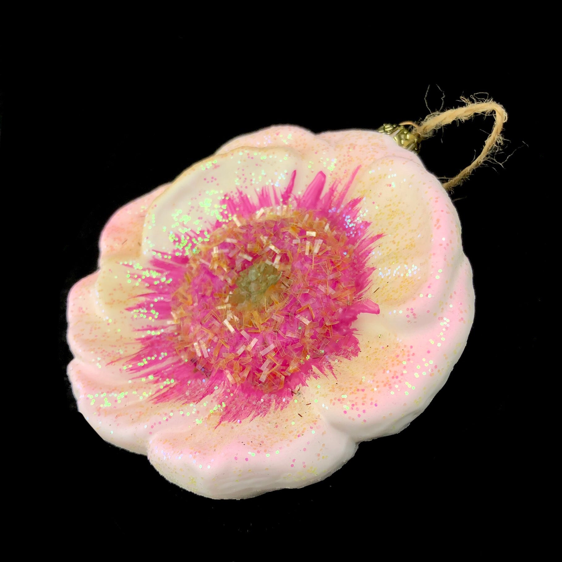 Side view of glittered flower with white petals and pink interior. 