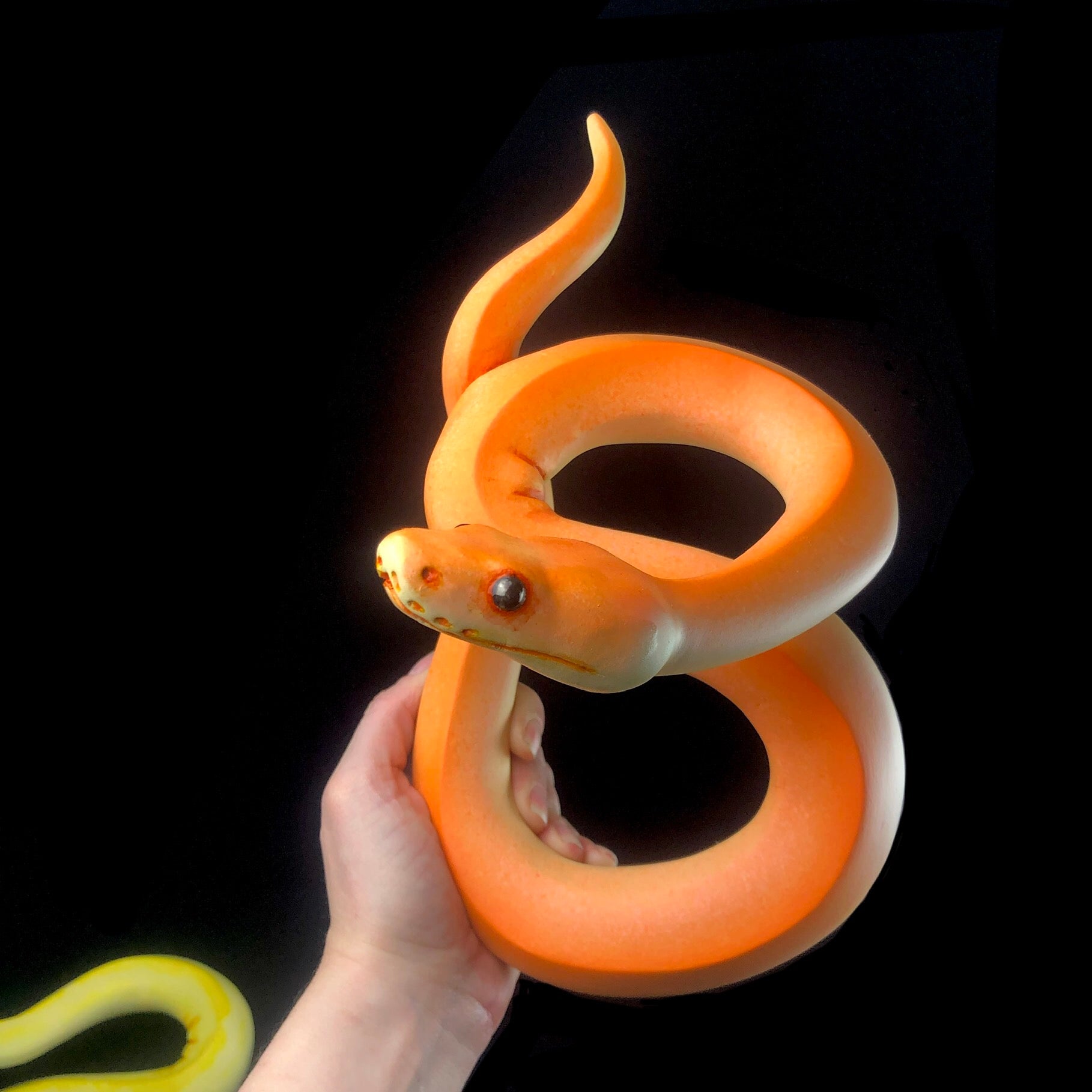 Front view of Orange Wall Hanging Snake Sculpture in hand for size reference