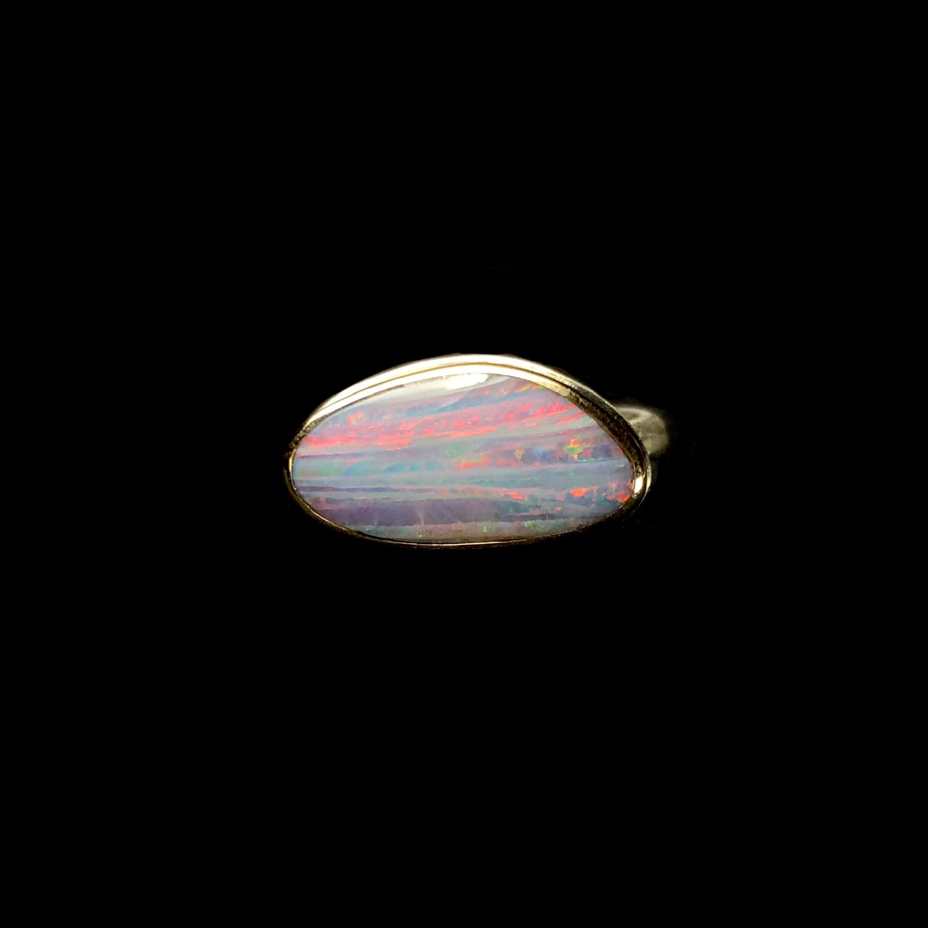 Asymmetrically shaped Boulder Opal with layers of pink, grey, purple, and green in the stone