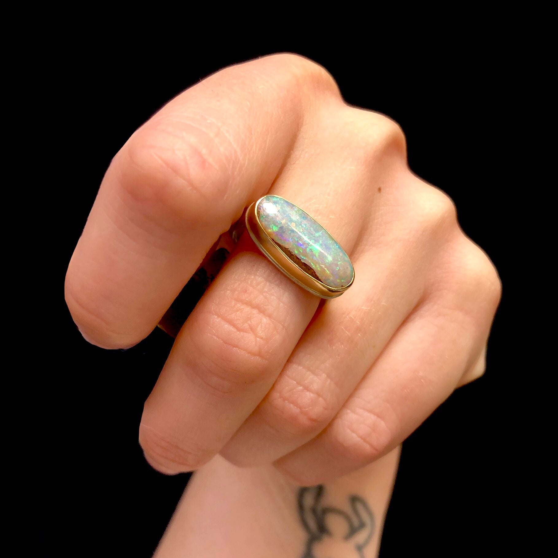 Smooth surface of Fossilized Opalized Wood Ring reflecting light on stone shown on hand