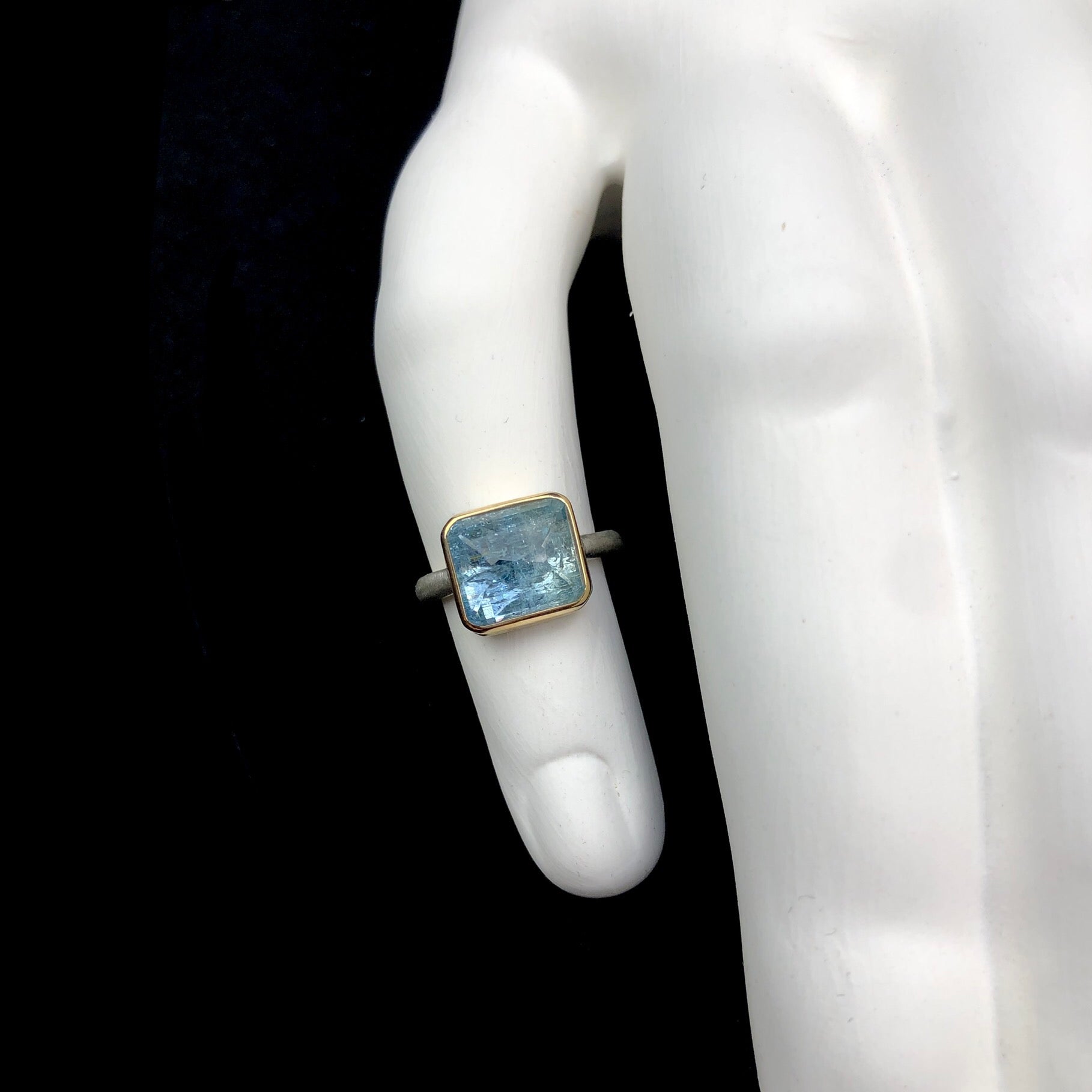 Light blue aquamarine stone ring shown on white ceramic finger