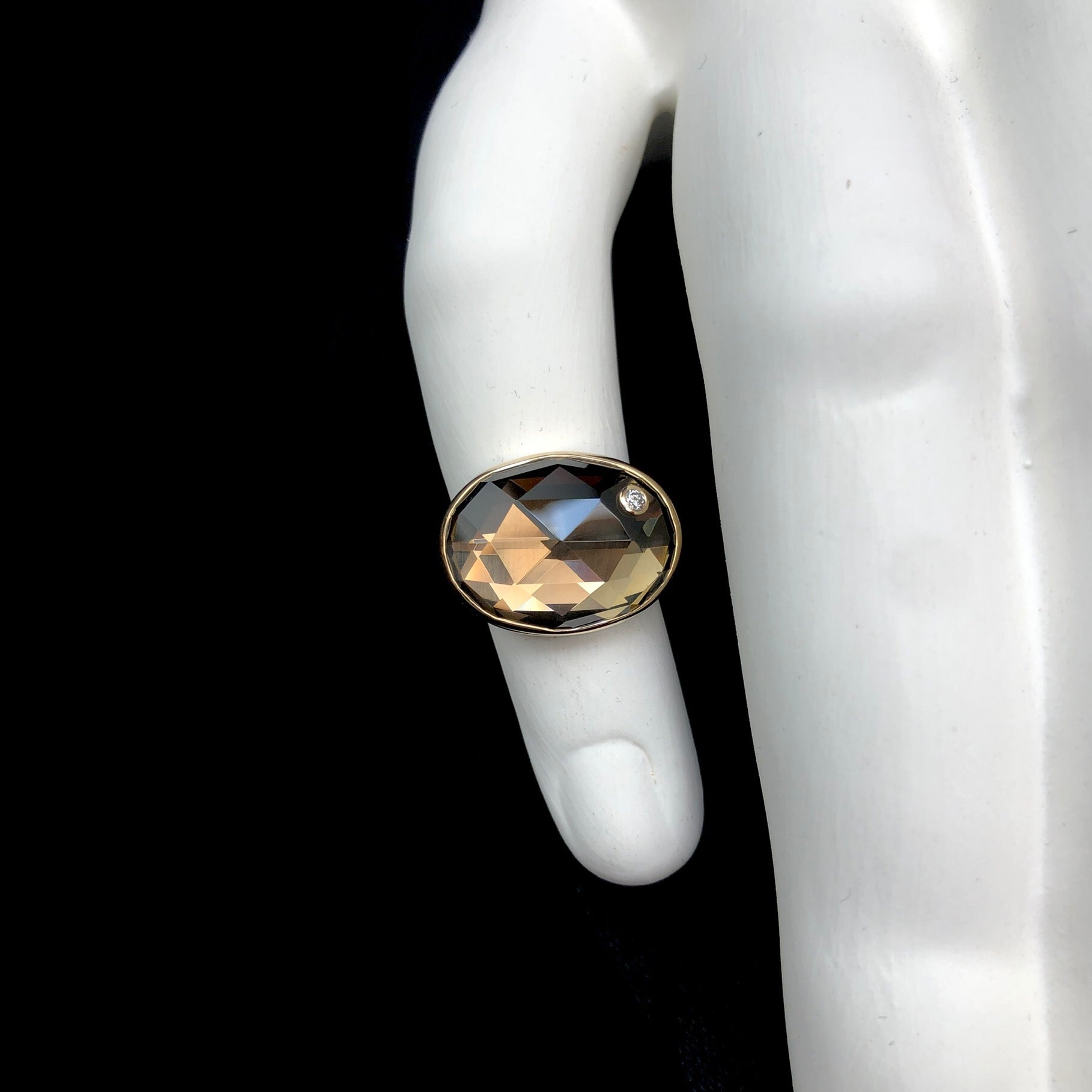 Top view of oval shaped smokey quartz ring on white ceramic finger