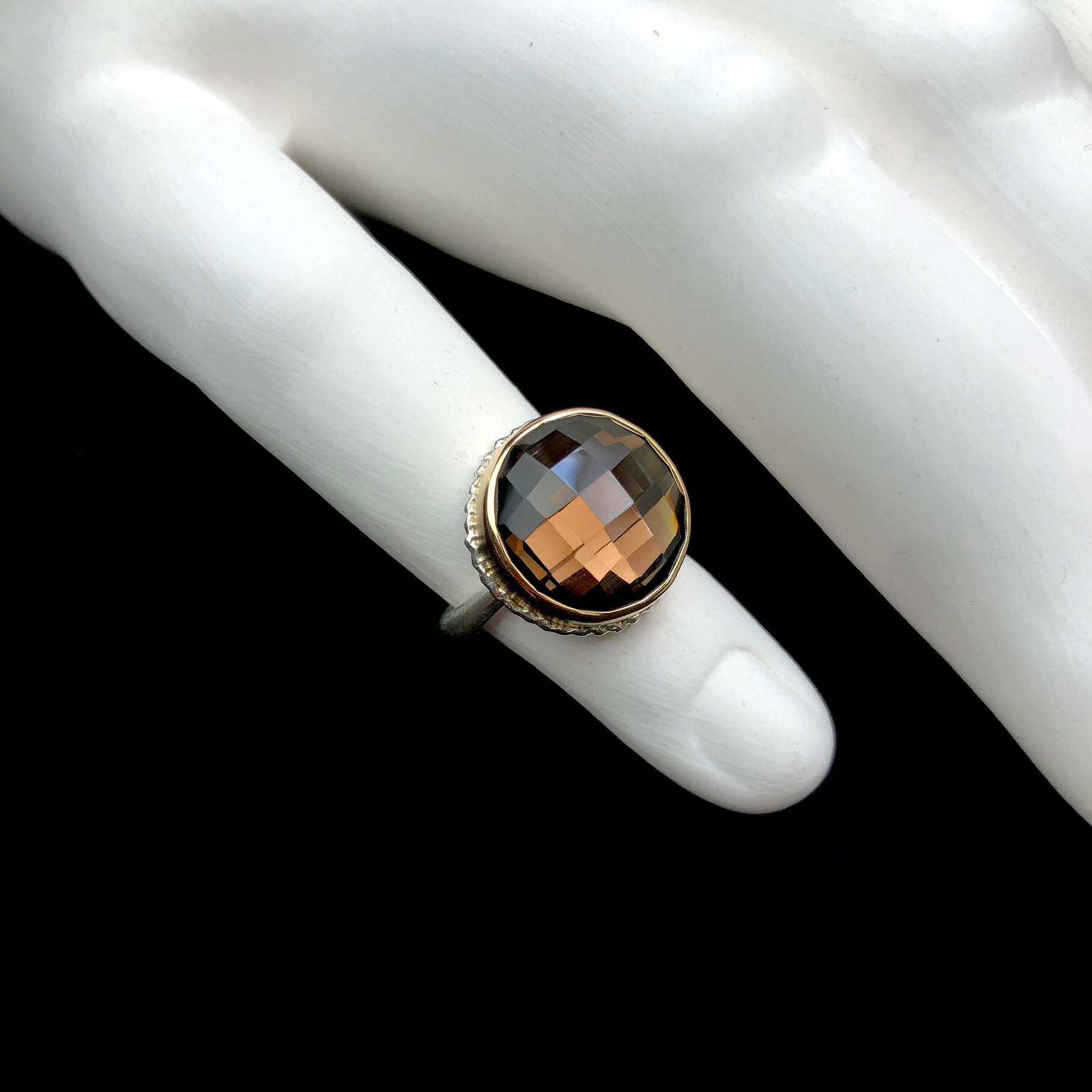 Round smokey quartz ring shown on white ceramic finger
