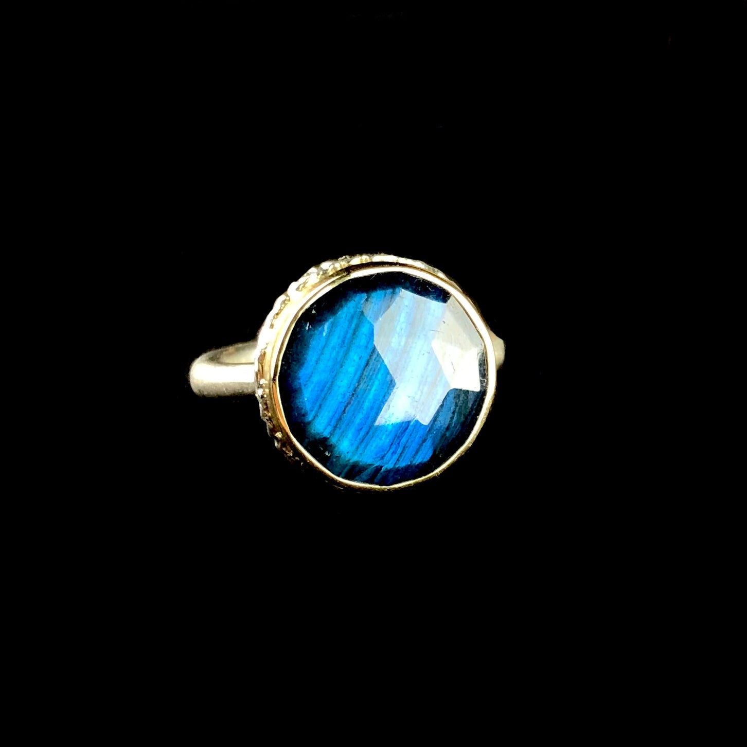 Front view of round iridescent blue/green stone ring
