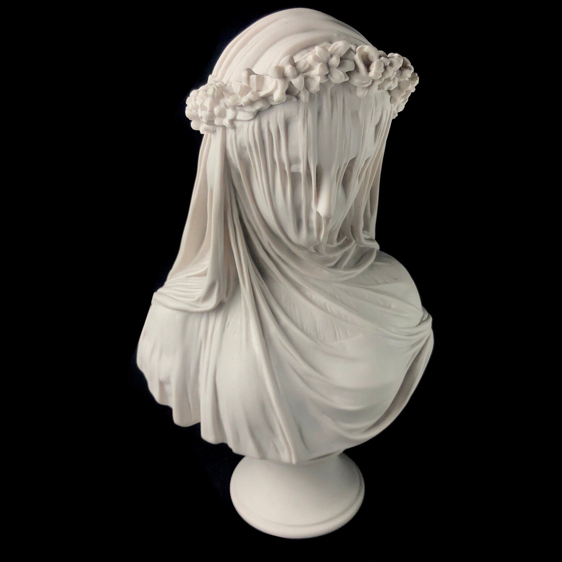 Top front view of white marble bust depicting a vailed bride