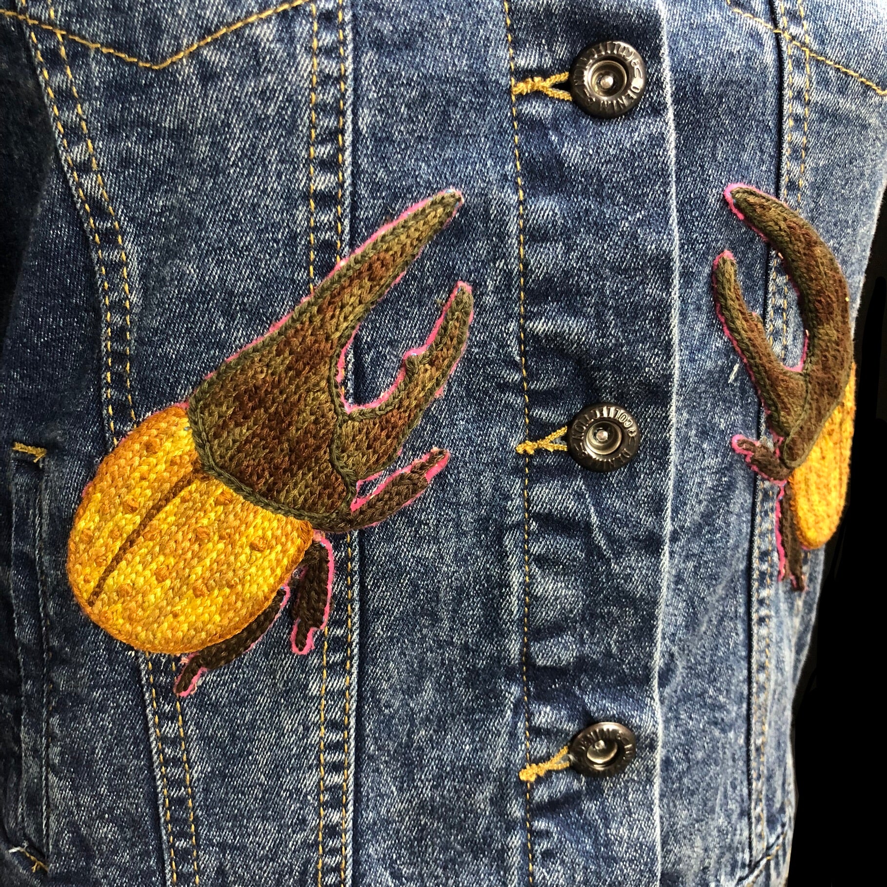Detail view of Dynasties Hercules beetle patches shown on front of Beetle jean Jacket