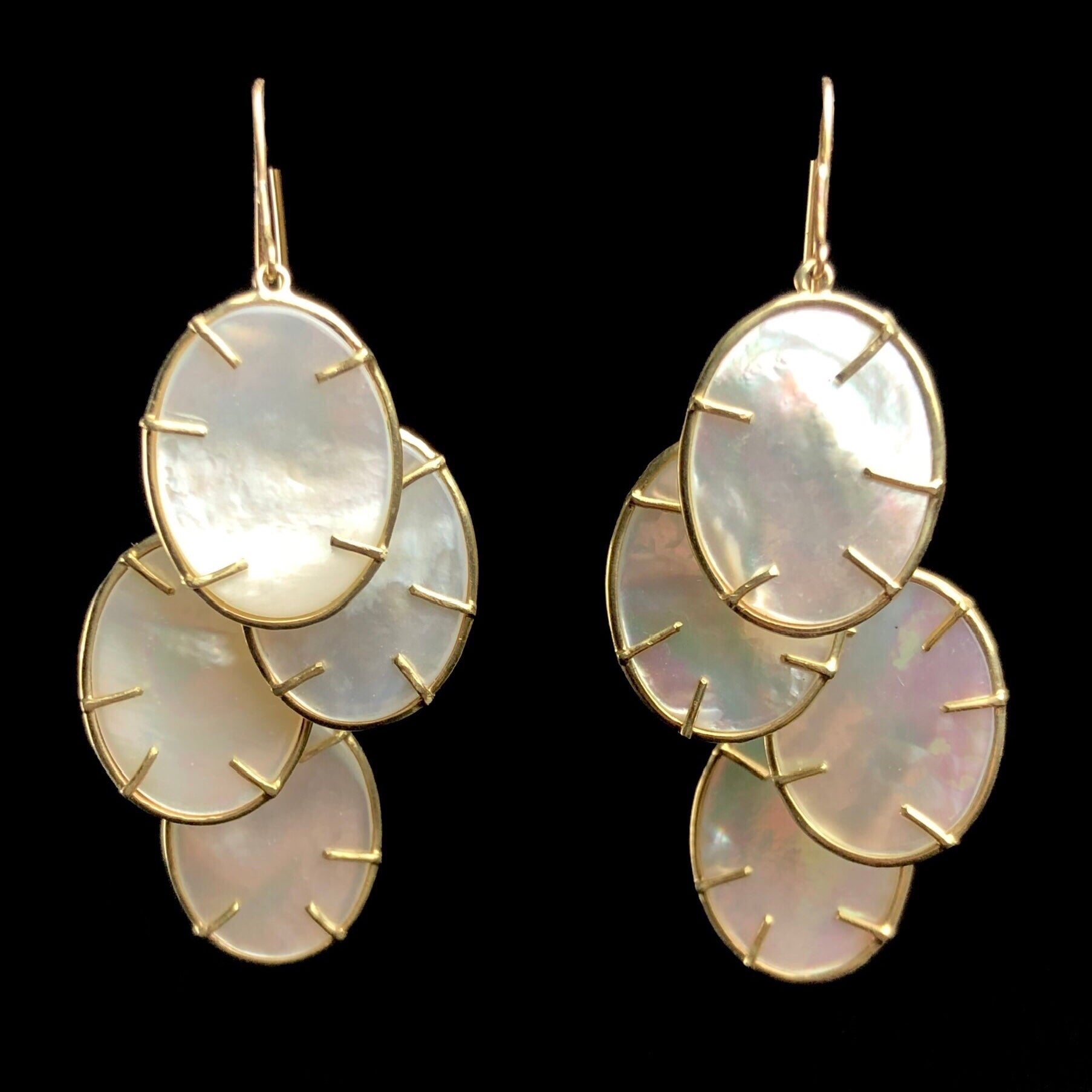 Silver Dollar Earrings hanging side by side each with four white, oval medallions held by gold prongs 