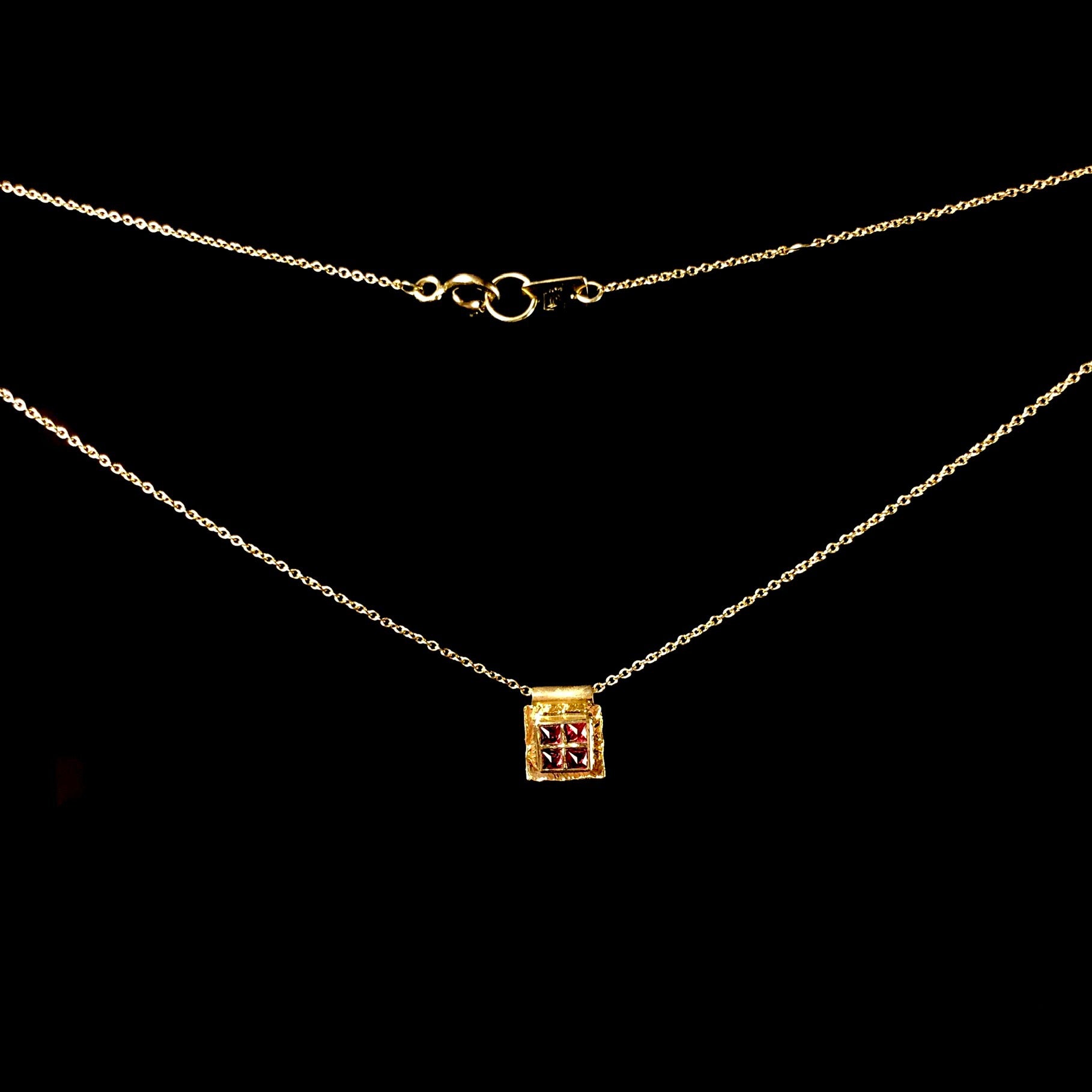 Four red spinel stones set in square platform on gold chain with clap showing