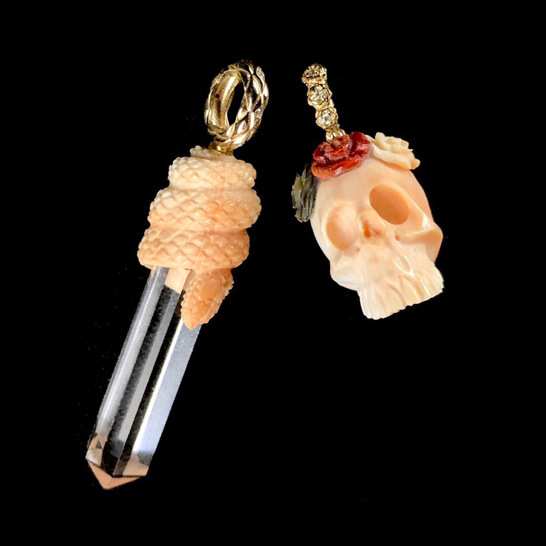 Clear crystal with light orange snake coiled about its top with gold bail net to matching skull carving