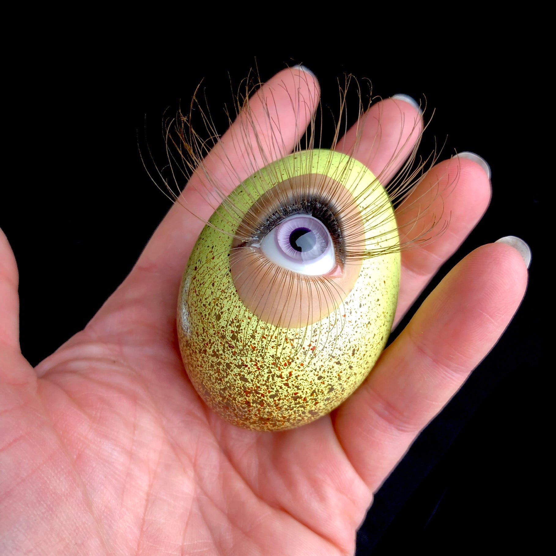 Verona the Chicken Egg with purple eye and brown lashes shown in hand