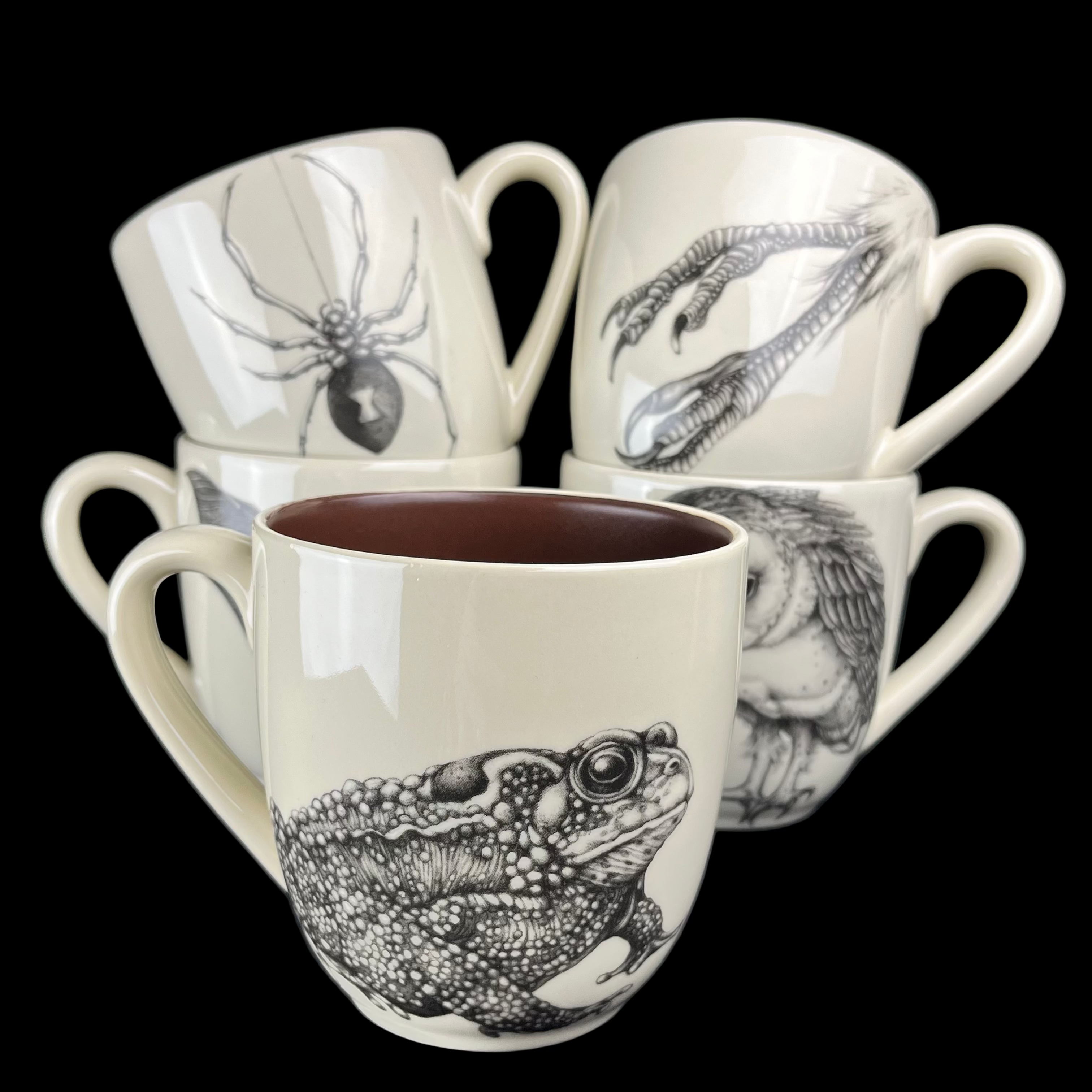Set of four mugs with black and white animal illustrations on a dark background