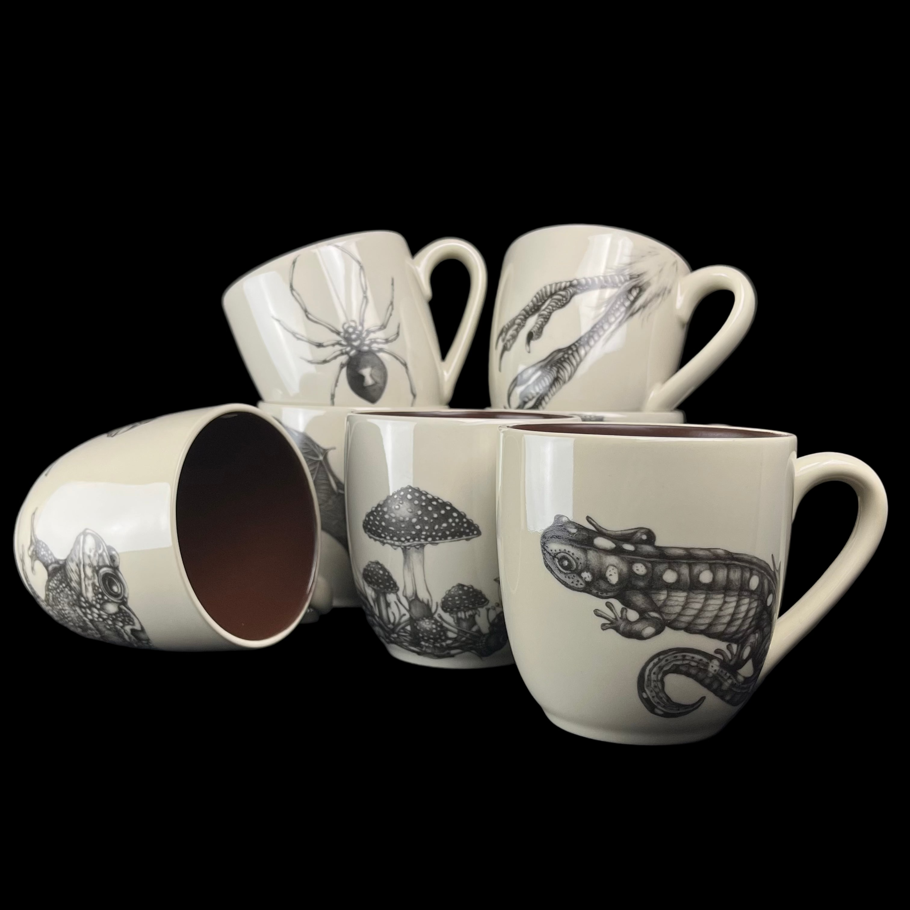 Set of ceramic mugs with black line art designs on a dark background