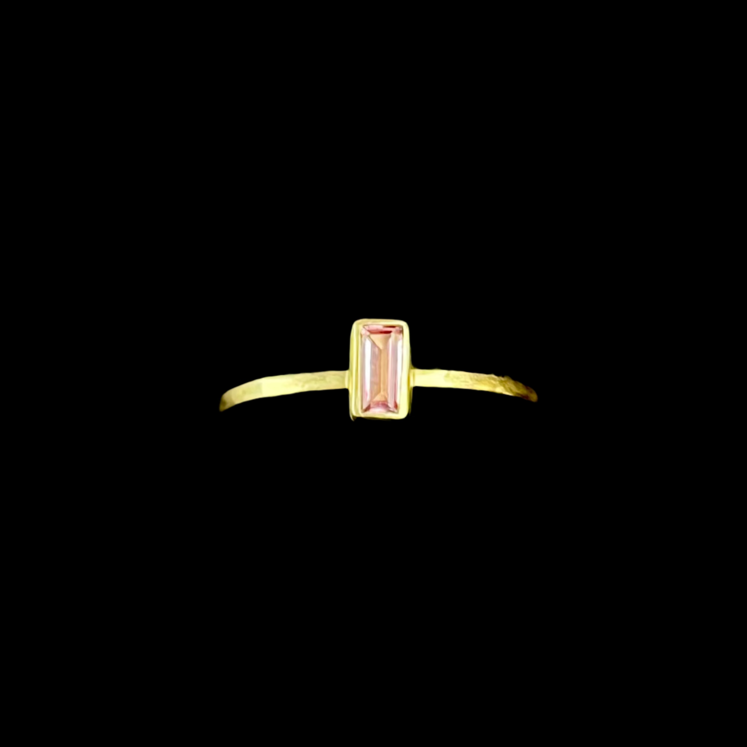 Gold ring with a pink gemstone on a black background