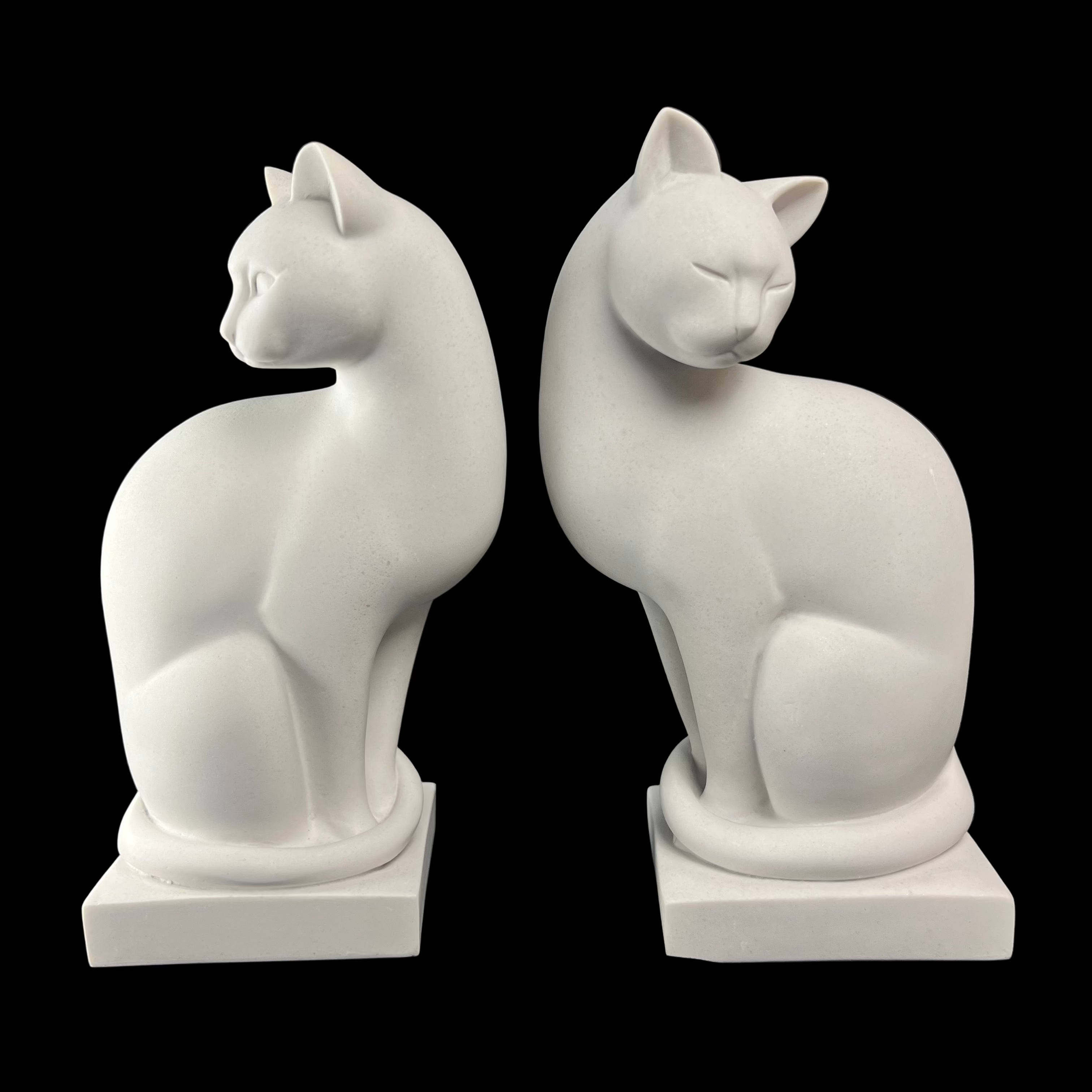 Two white marble cat sculptures looking left and right