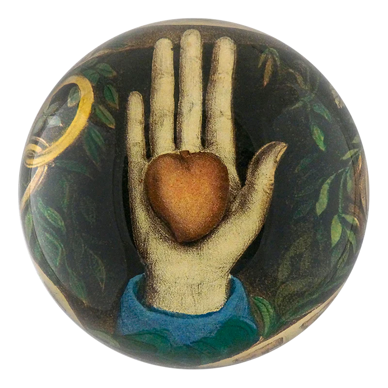 Decorative object with a hand holding a heart design on a dark background