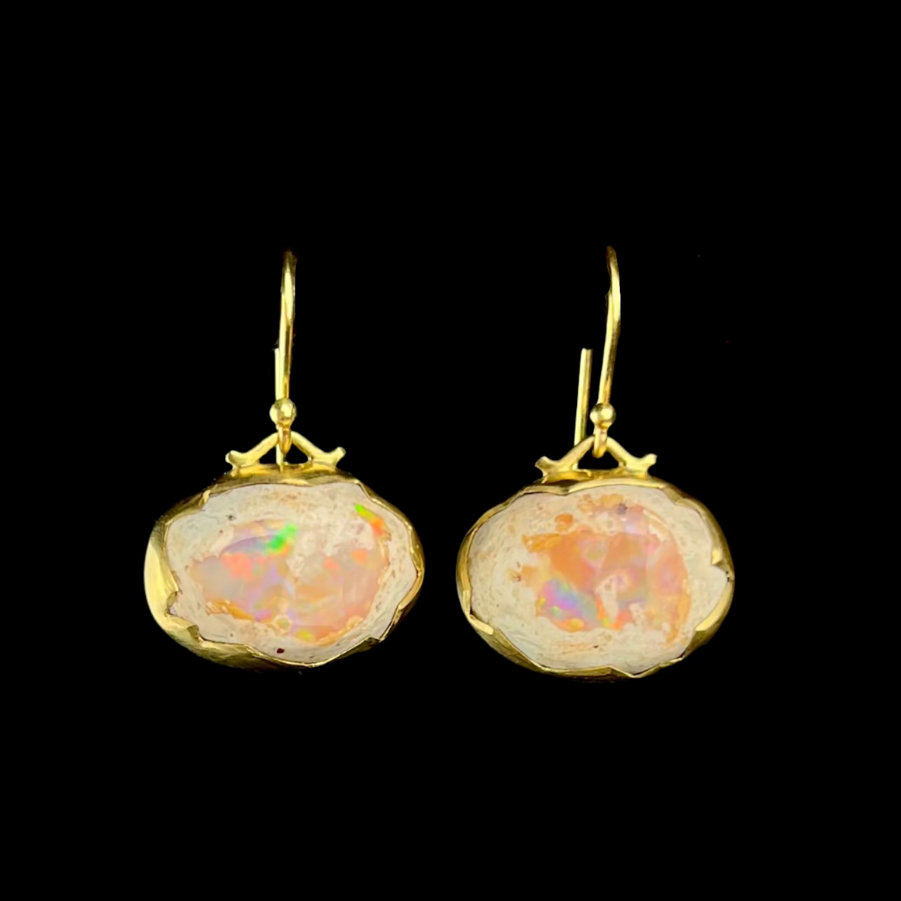 Opal earrings with gold frames on a black background